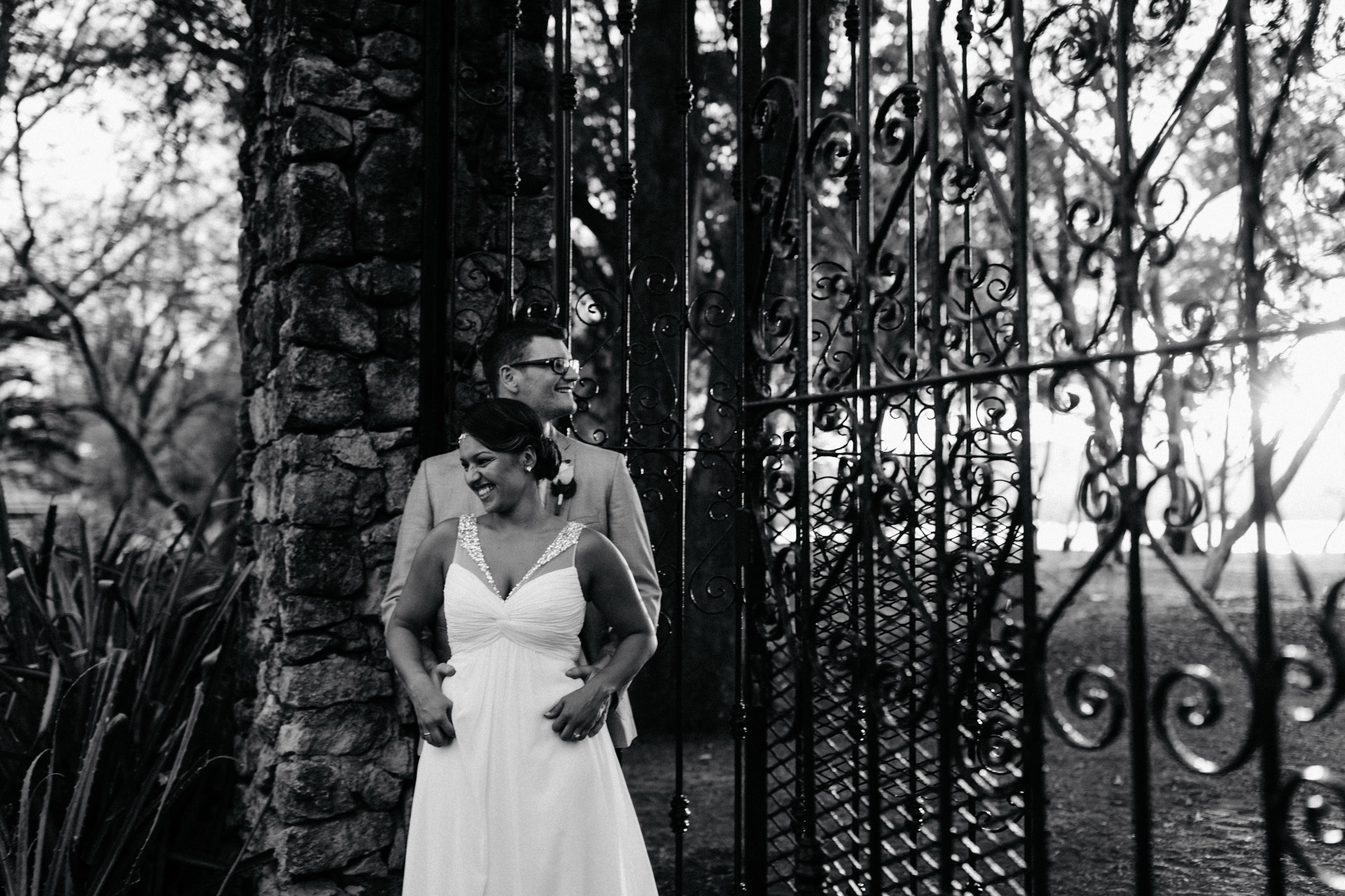 Heiraten in Costa Rica - Brautpaar vor einem schmiedeeisernen Tor, Braut lacht