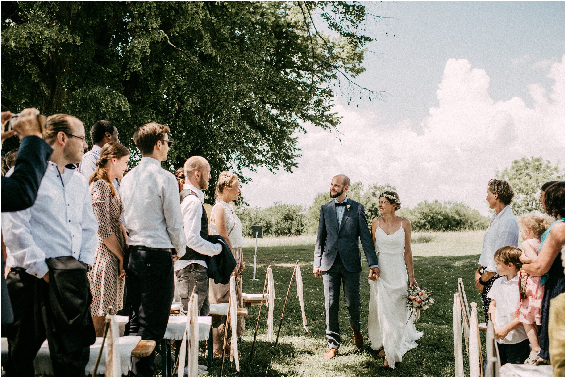 Wiesenhochzeit: Brautpaar läuft durch die stehenden Gäste zum Trautisch