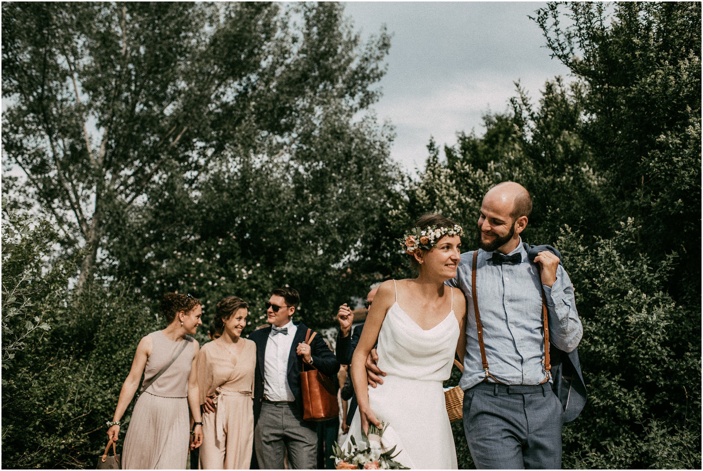 Wiesenhochzeit: Brautpaar läuft Arm in Arm vorne weg