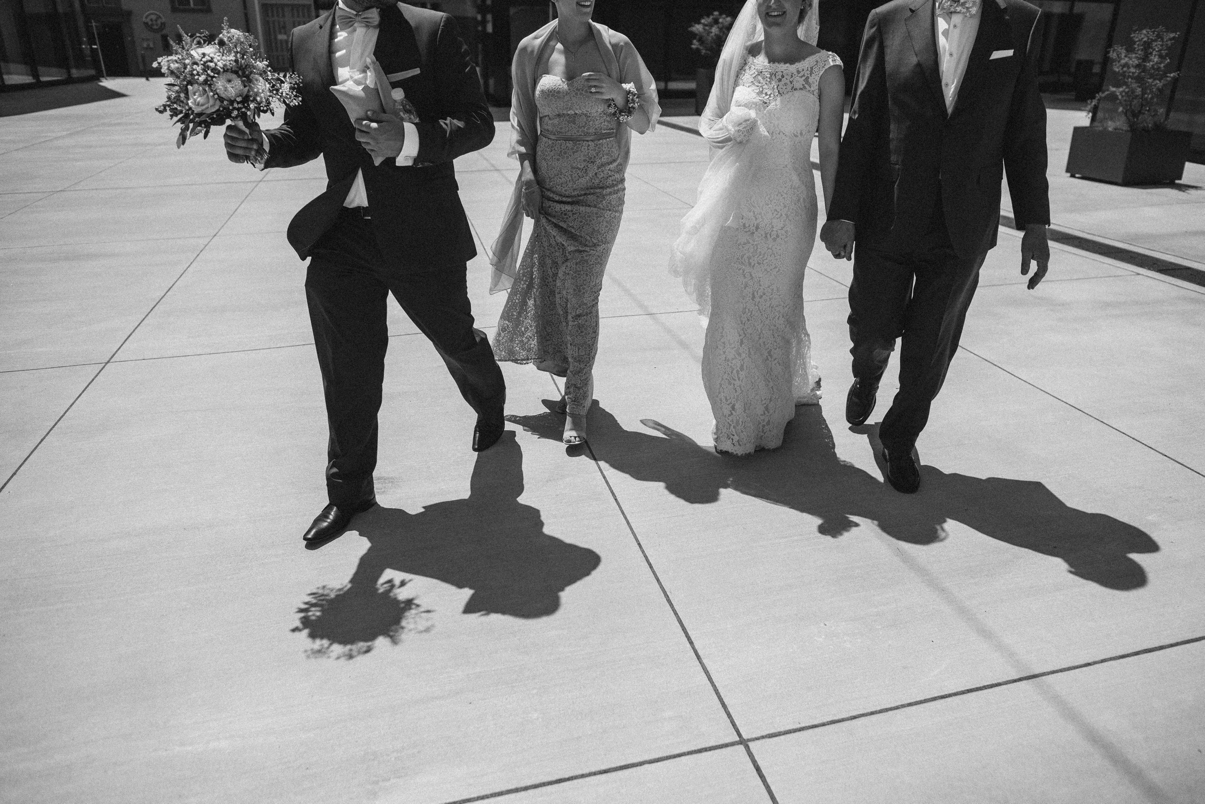 Hochzeit in der Schweiz: Braut Hand in Hand mit Brautvater und zwei Gästen laufen zur Trauung