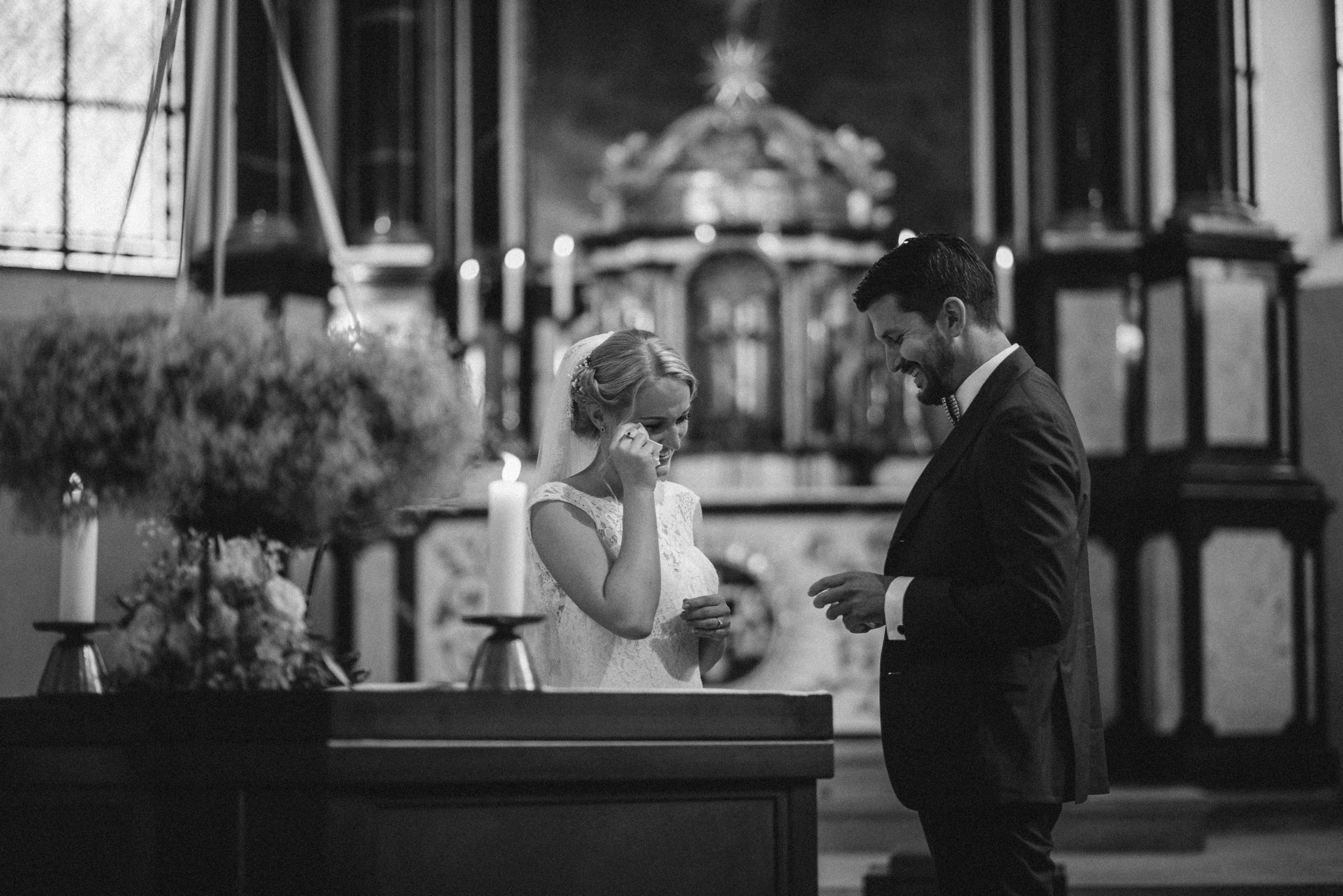 Hochzeit in der Schweiz: Brautpaar vor dem Altar, Braut wischt sich eine Träne aus dem Auge