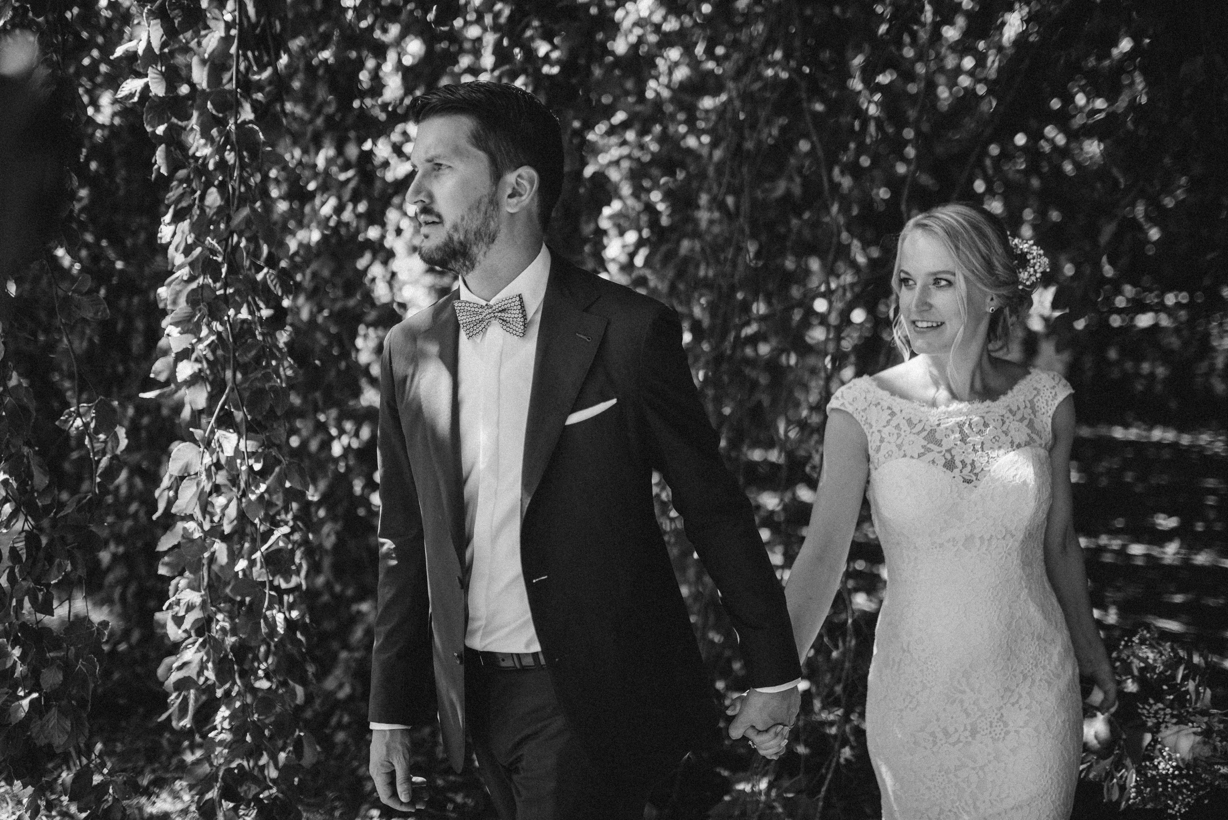 Hochzeit in der Schweiz: Brautpaar läuft Hand in Hand durch einen Garten