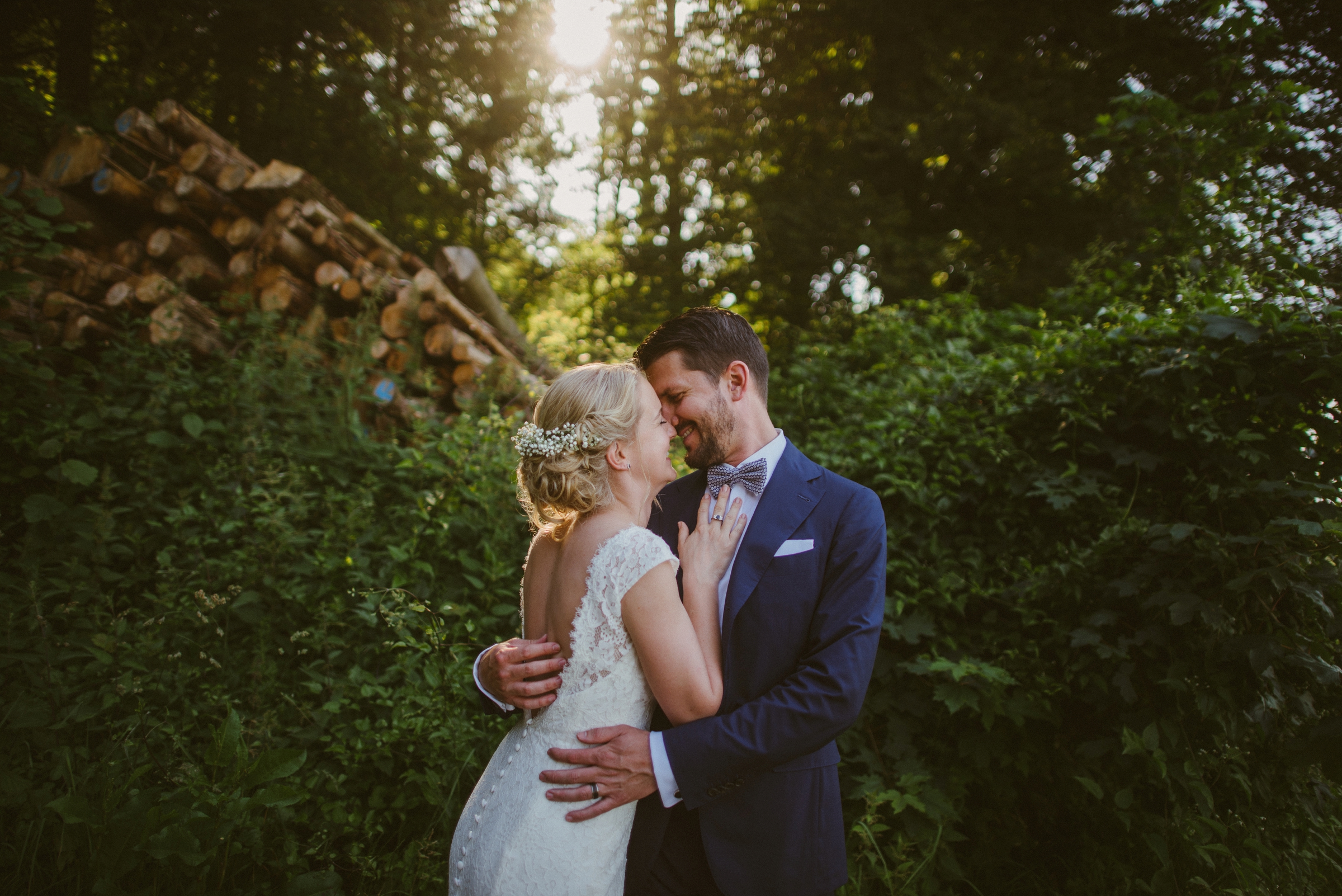 Hochzeit in der Schweiz: Brautpaar hält sich im Arm, die Sonne scheint durch die Bäume