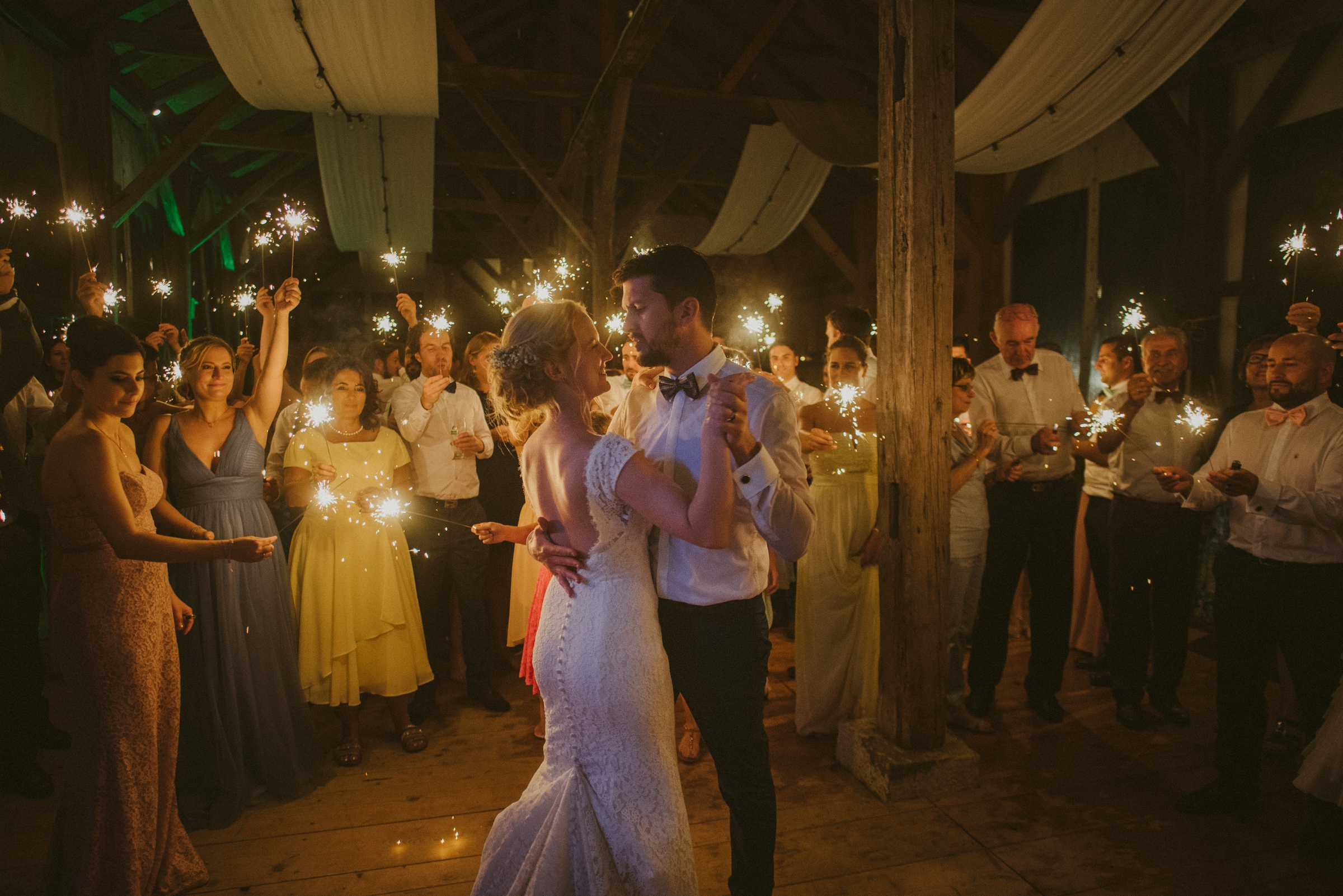 Hochzeit in der Schweiz: Brautpaar tanzt Hochzeitstanz, im Hintergrund die Gäste mit Wunderkerzen