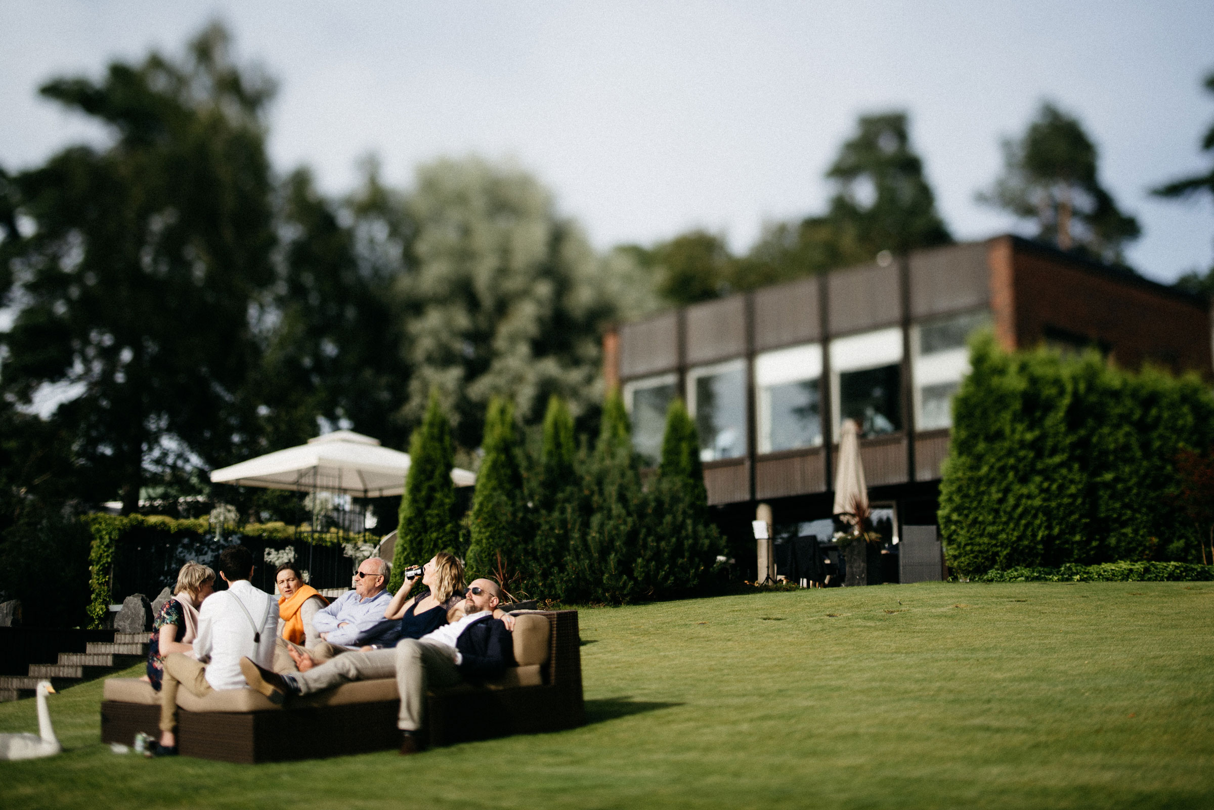 finnische Hochzeit: Gäste sitzen entspannt im Garten der Hochzeitslocation