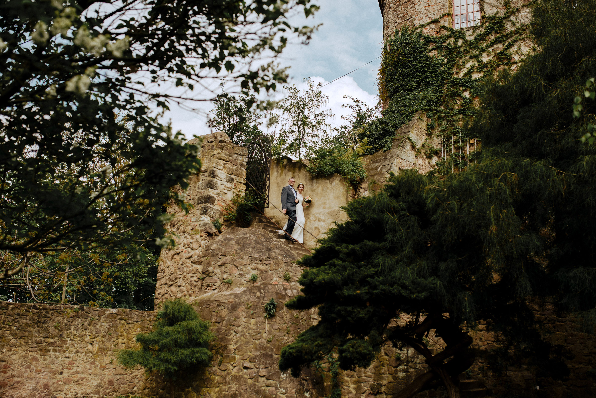 Outdoor-Hochzeit: die Braut wird über die steinerne Treppe vom Brautvater in den Schloßgarten zur Trauung geführt