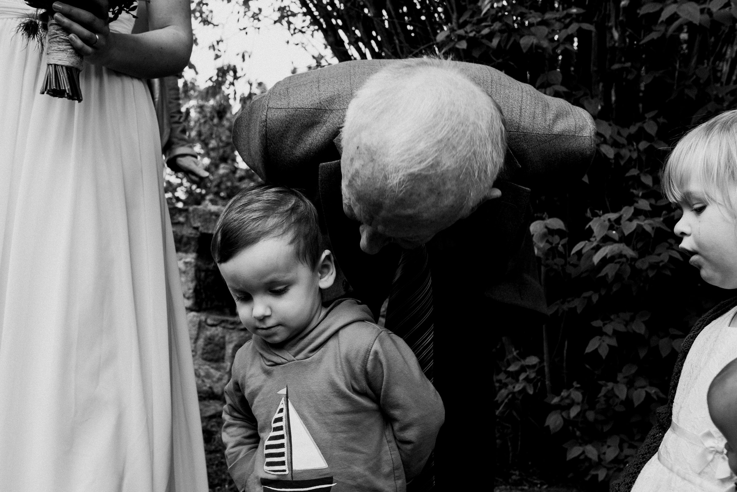 Outdoor-Hochzeit: Hochzeitsgast beugt sich zu einem kleinen Jungen hinunter