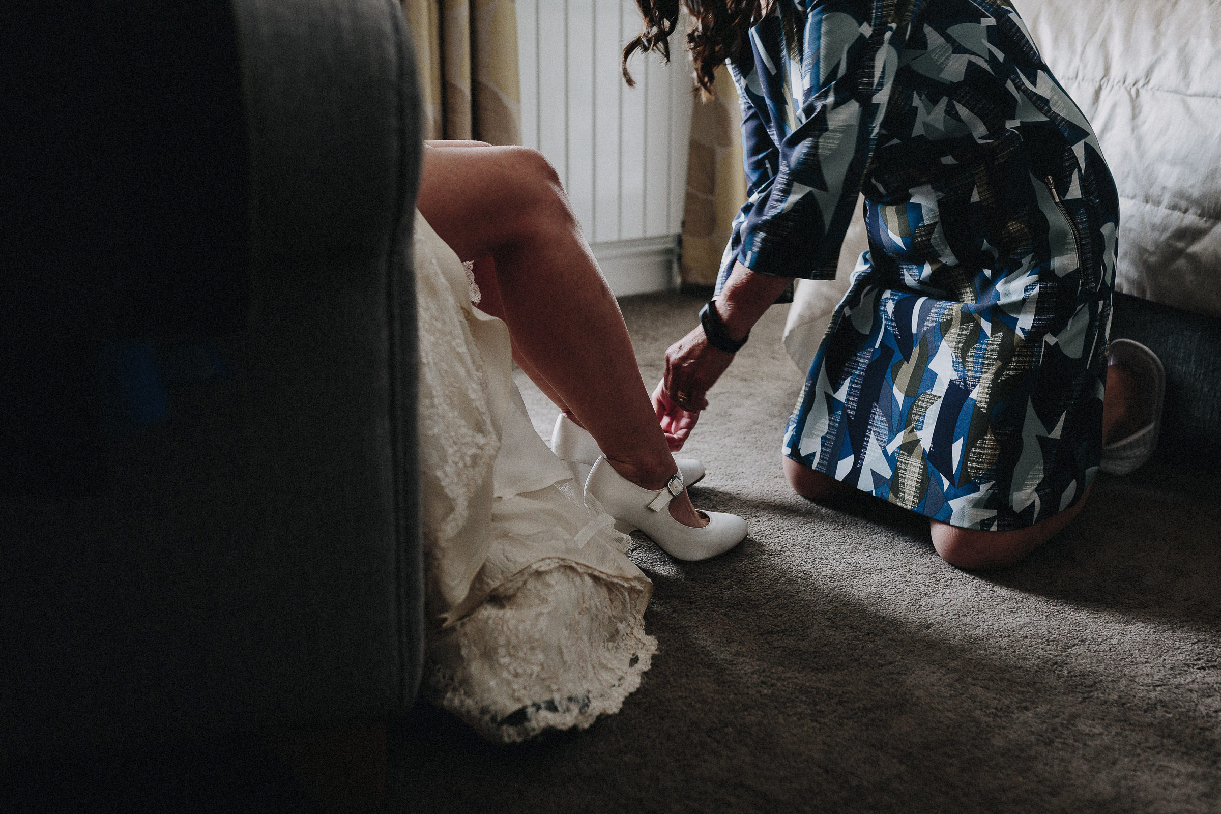 Britische Hochzeit: Brautjungfer zieht Braut Schuhe an