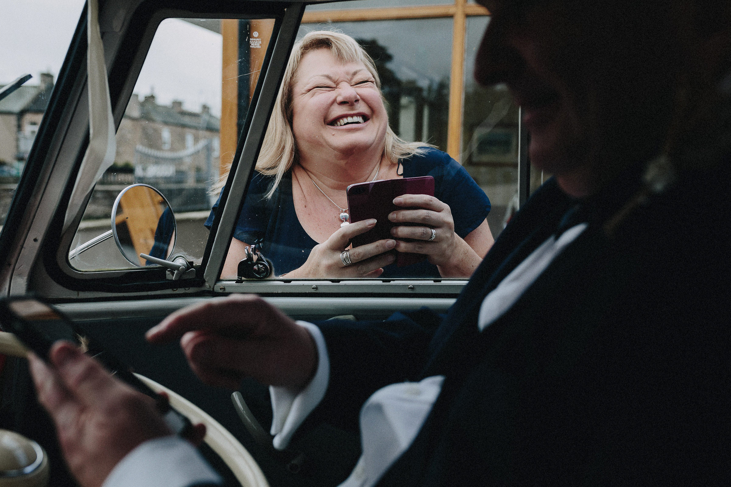 Britische Hochzeit: lachender Hochzeitsgast schaut ins Autofenster
