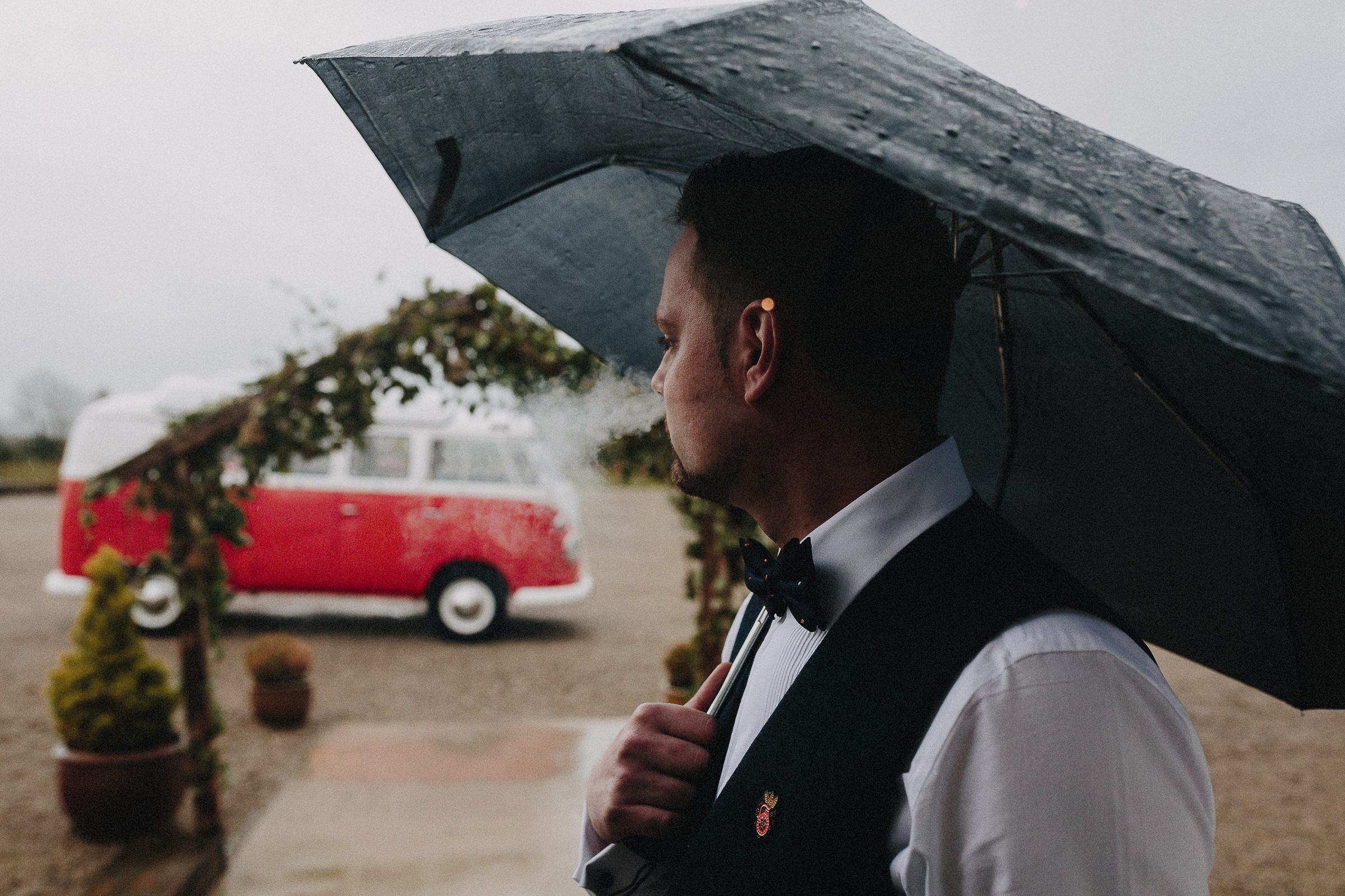 Britische Hochzeit: Hochzeitsgast mit Regenschirm und Zigarette