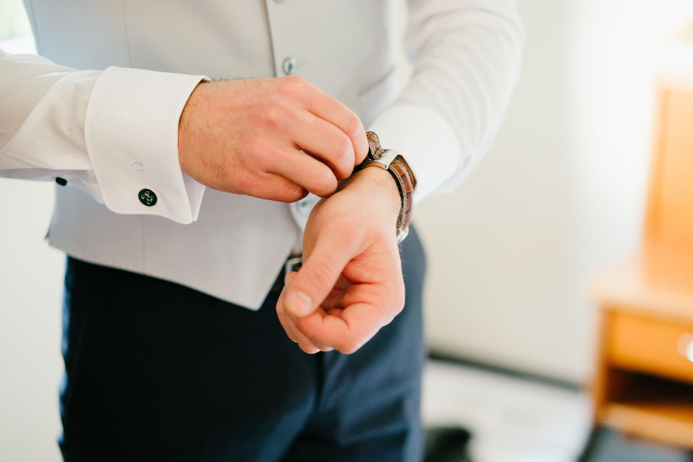 der Bräutigam der Silvester-Hochzeit bindet sich seine lederne Armbanduhr um