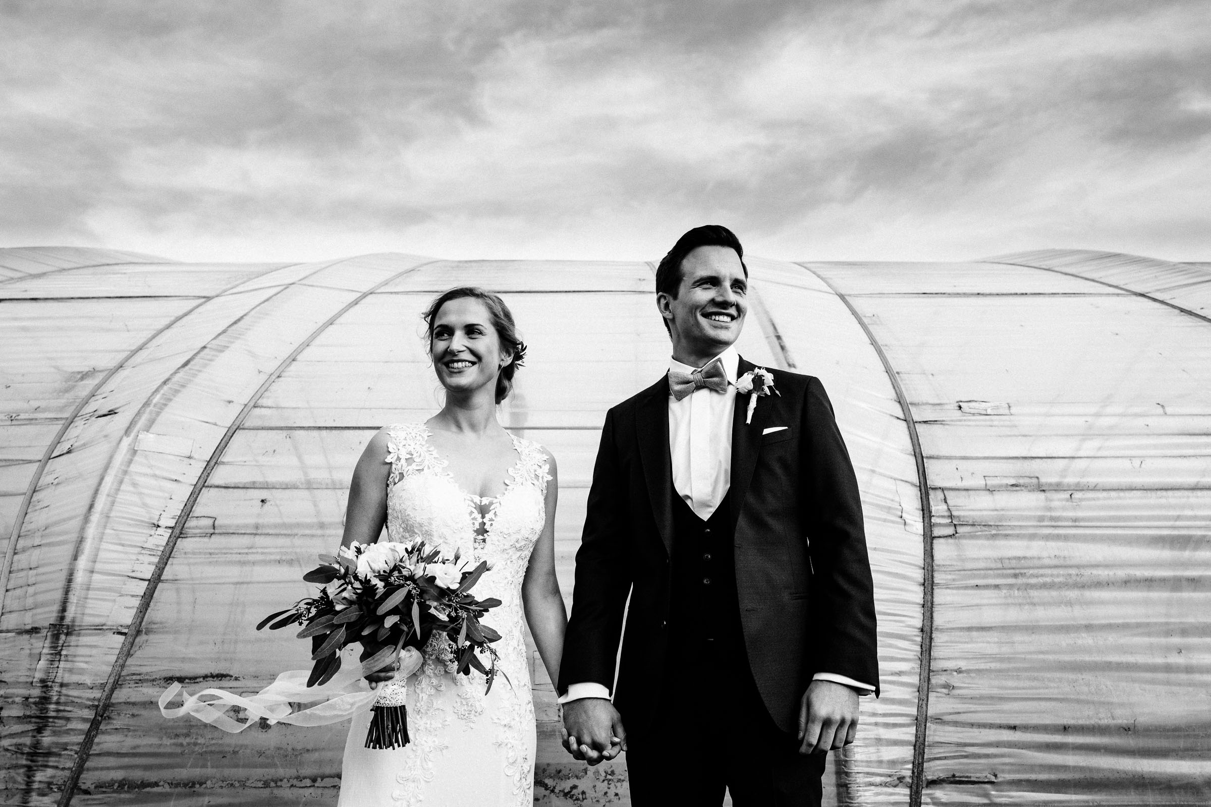 Portrait des Brautpaars der Silvesterhochzeit vor dem alten Gewächshaus Hand in Hand