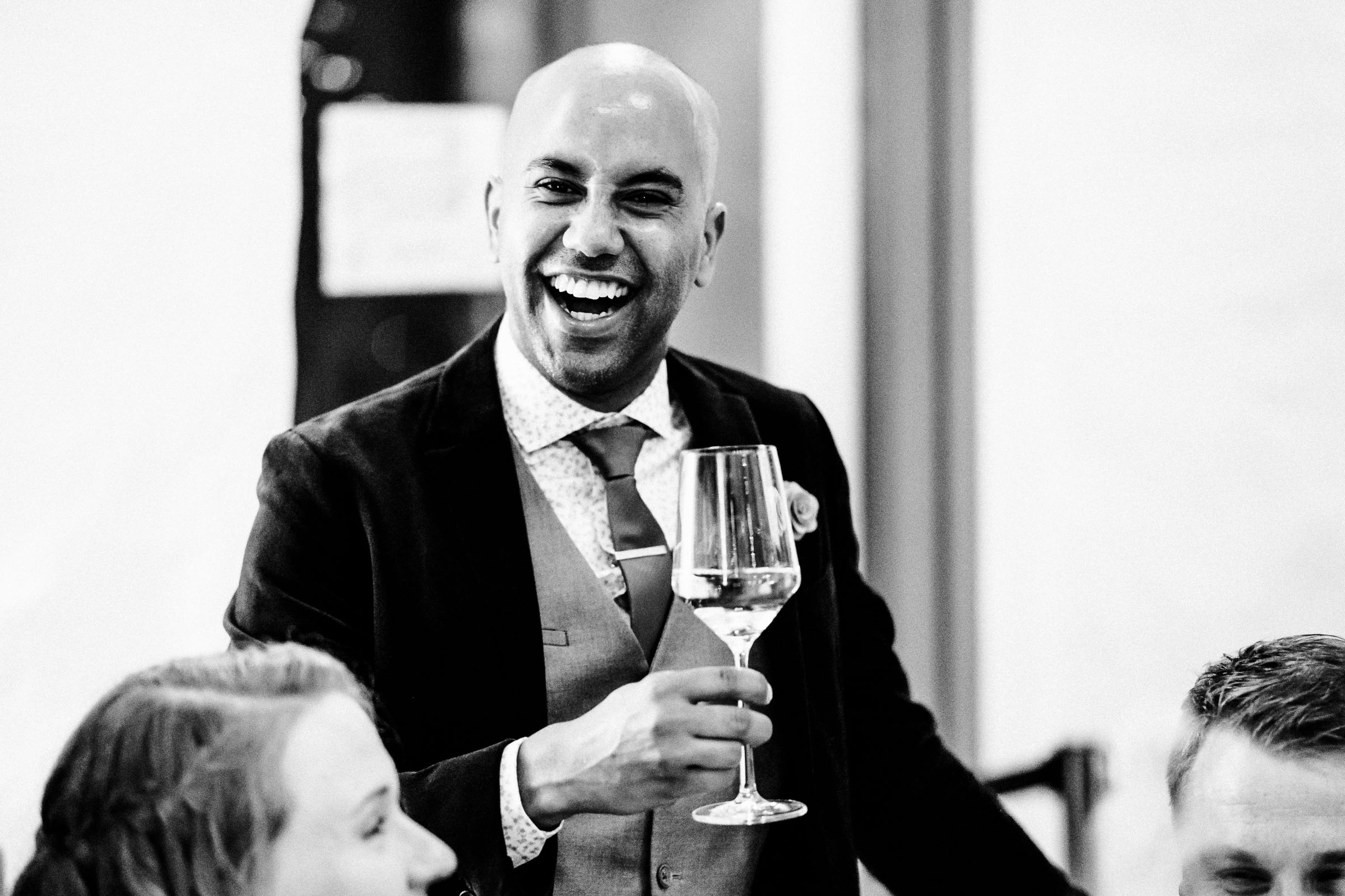ein lachender Gast der Silvester-Hochzeit mit Weißweinglas