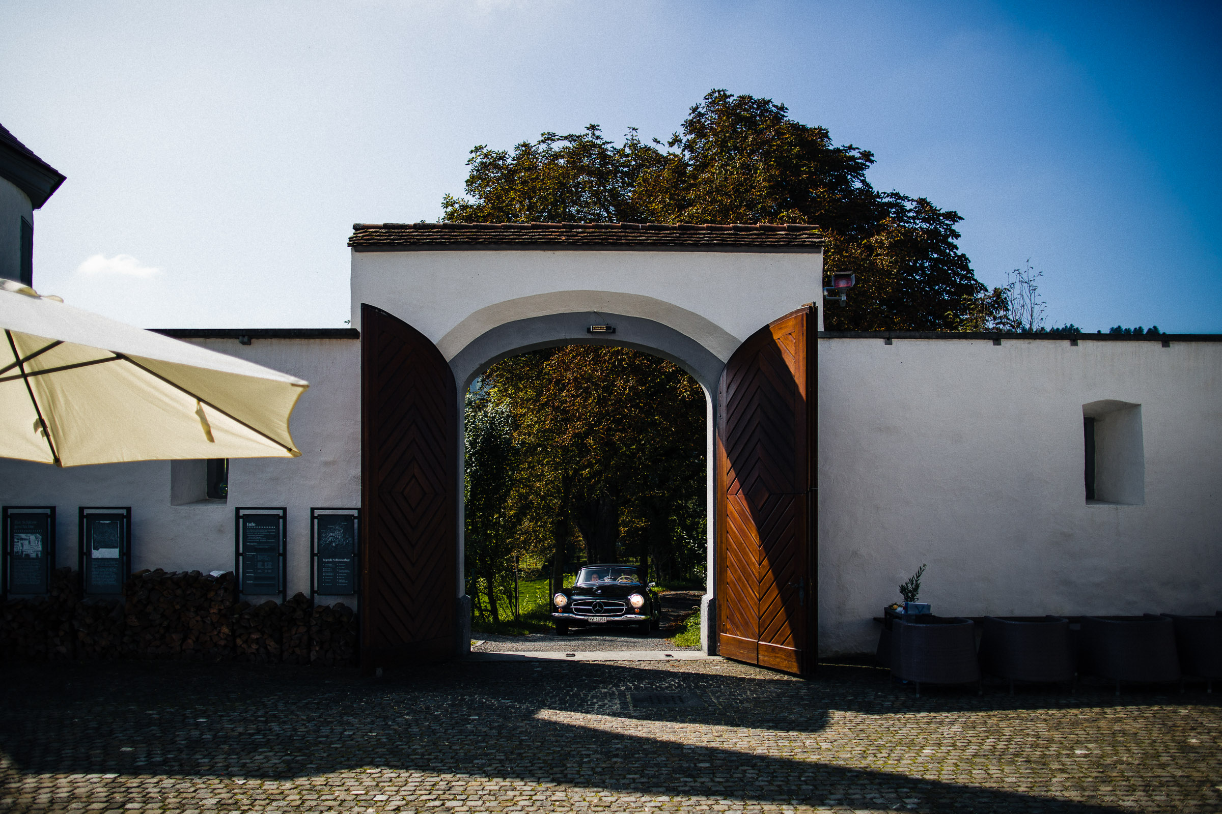 Schlosshochzeit: Brautpaar fährt in einem Oldtimer bei der Location ein