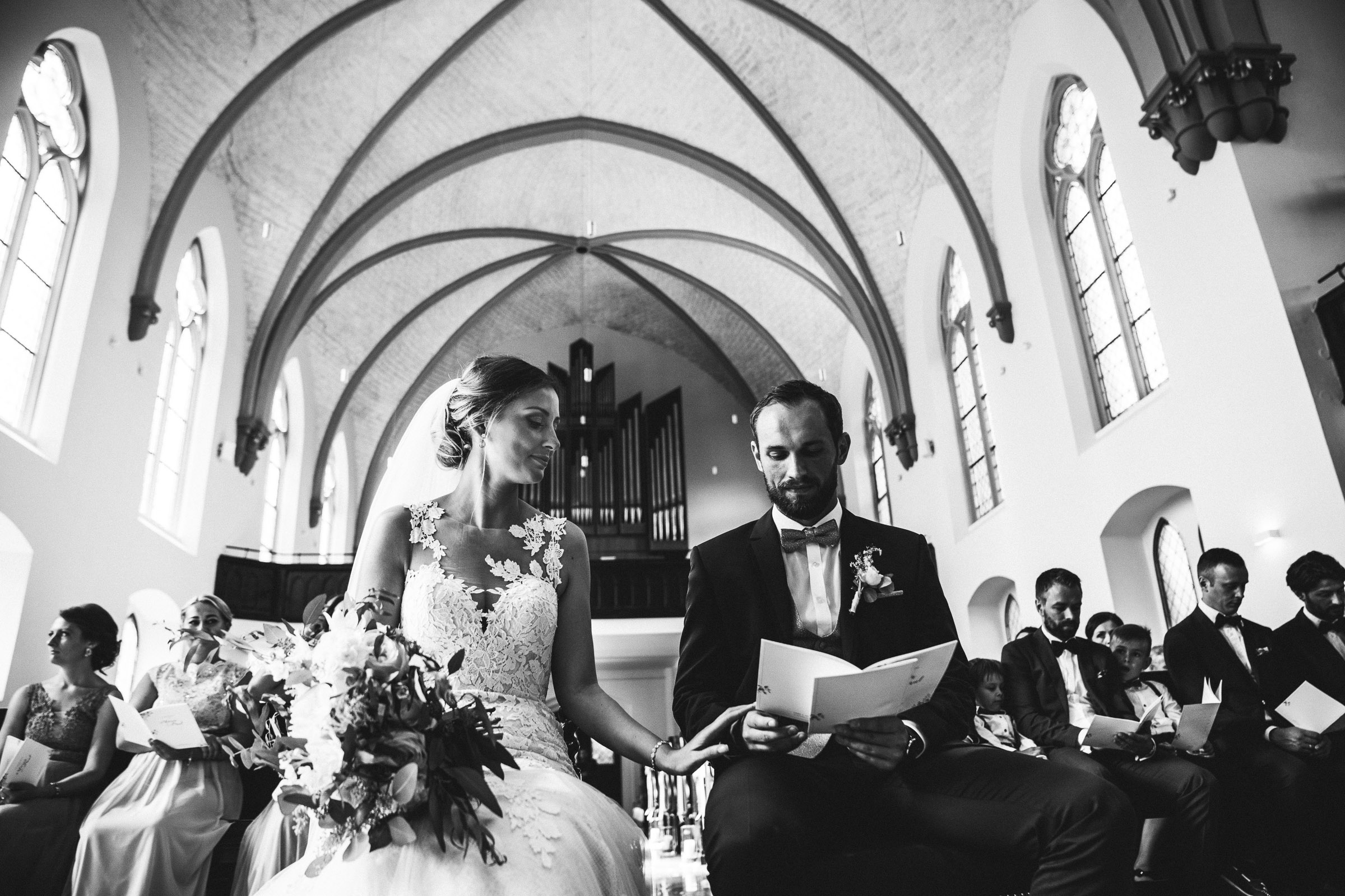 Septemberhochzeit: Braut berührt zärtlich den Arm des Bräutigams während der Trauung
