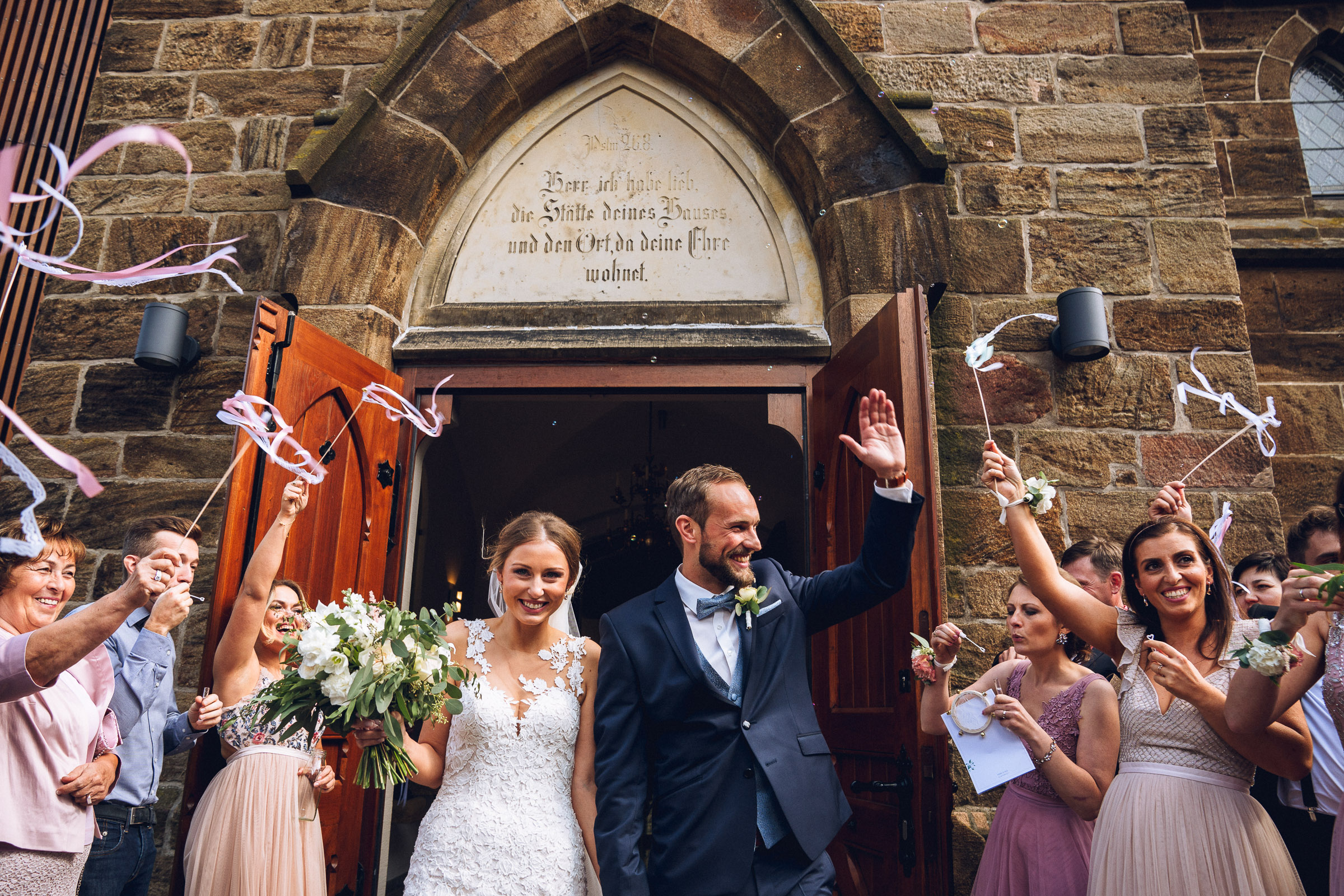 Septemberhochzeit: Auszug aus der Kirche, die Gäste schwenken Bänder