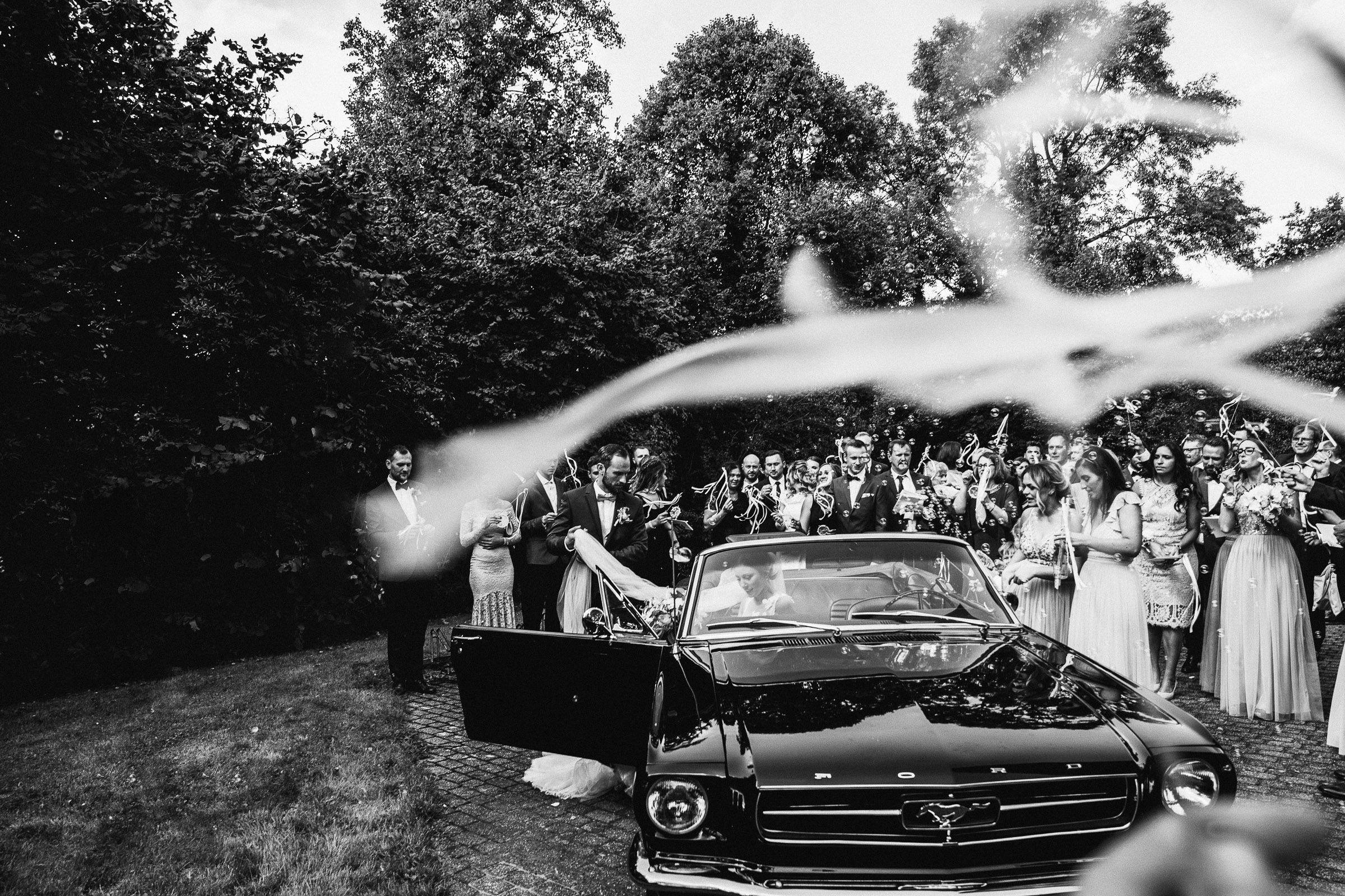 Septemberhochzeit: Brautpaar steigt in den schwarzen Mustang