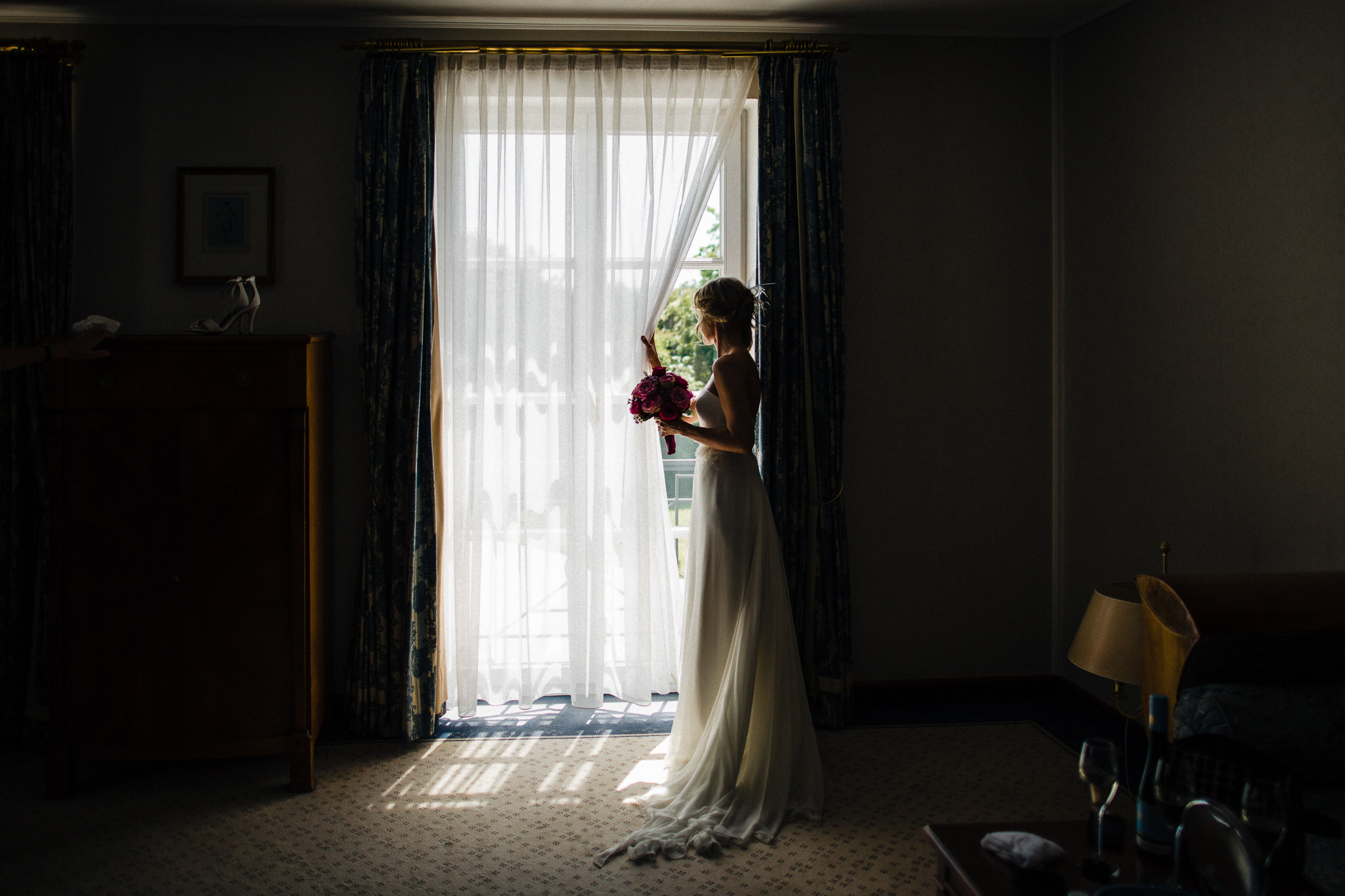 Schlosshochzeit: Braut schaut aus dem Fenster des Hotelzimmers