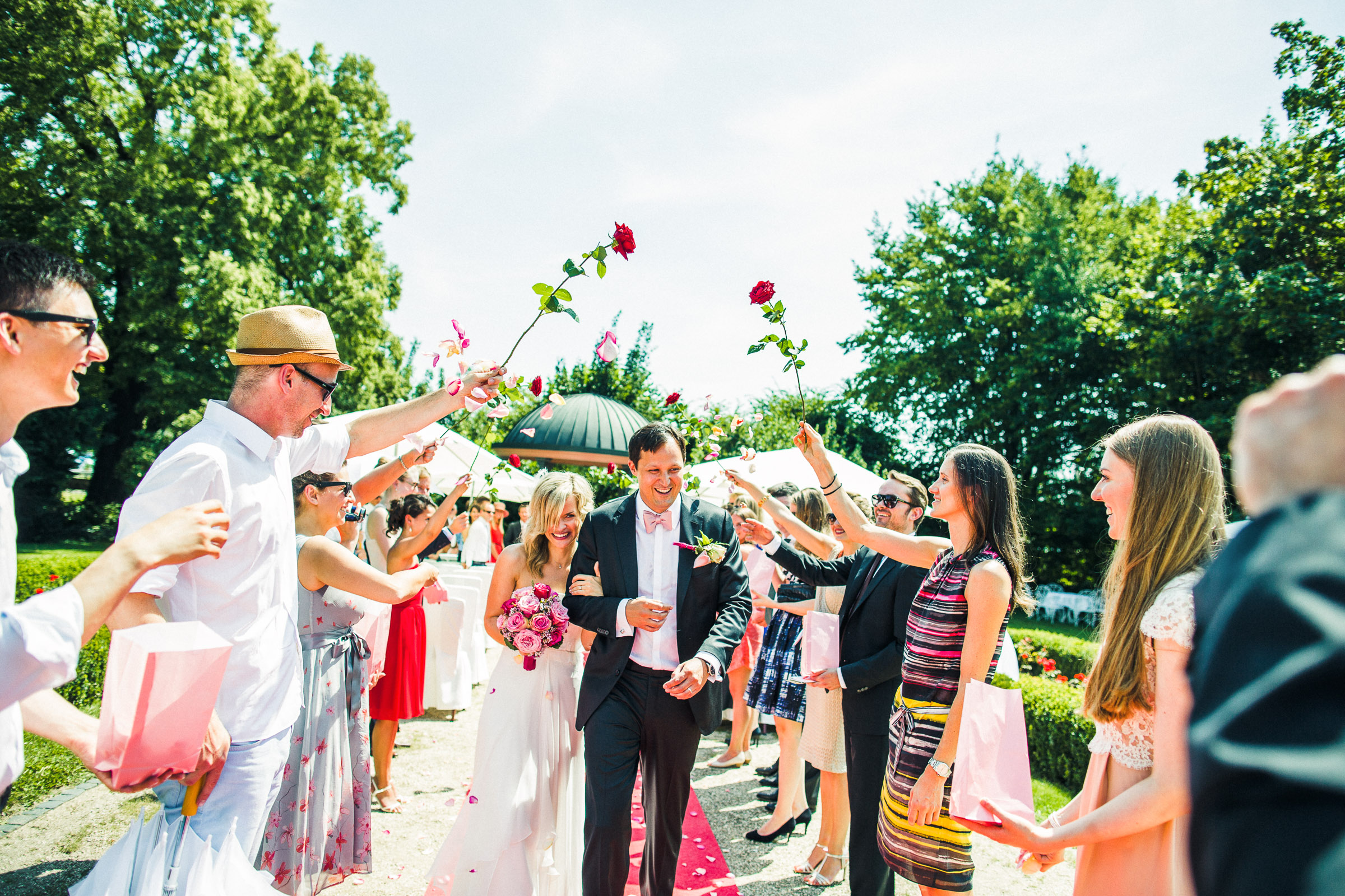 Schlosshochzeit: Brautpaar läuft durch ein Rosenspalier der Hochzeitsgäste