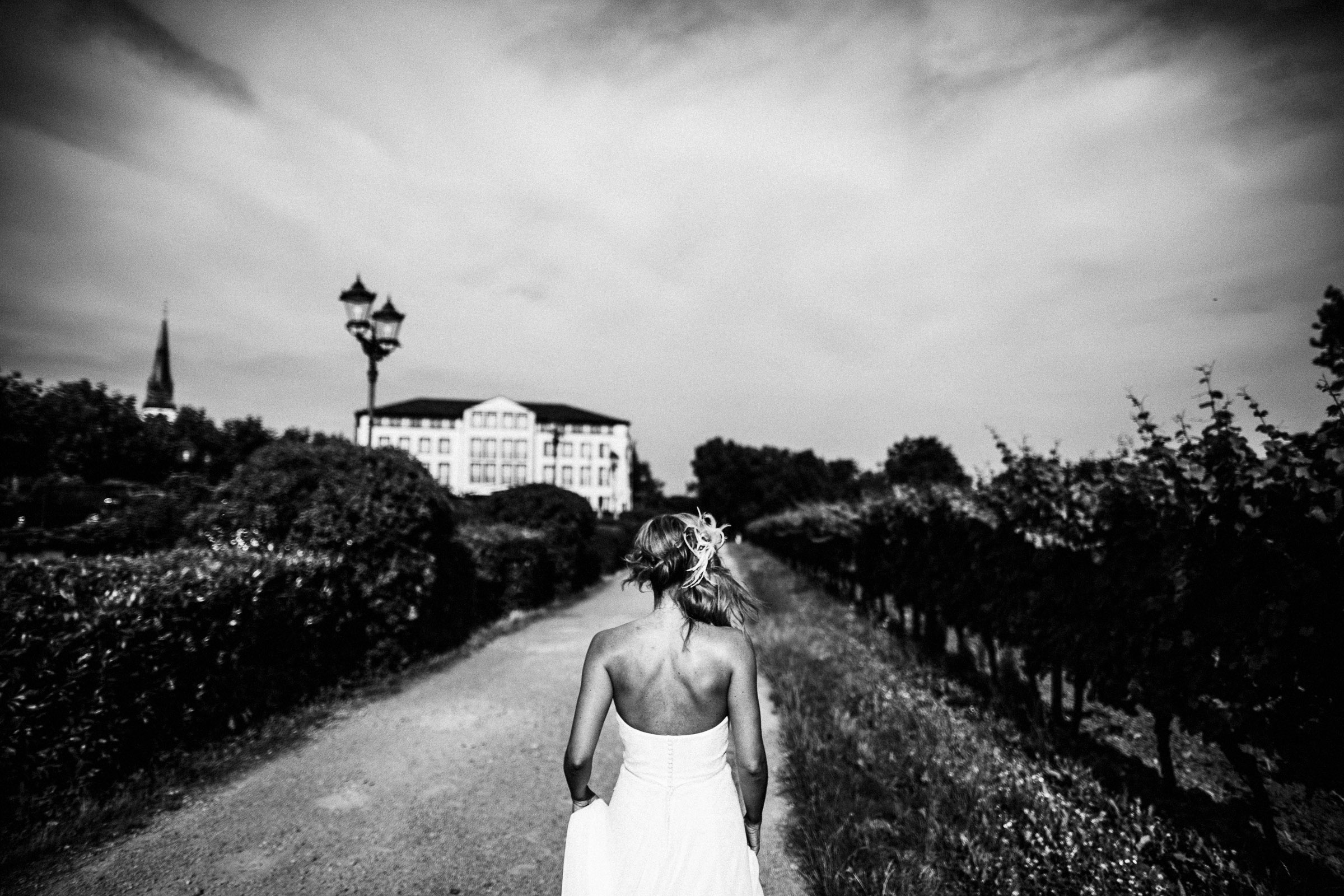 Schlosshochzeit: Braut läuft auf das Schloss zu durch die alten Weinreben