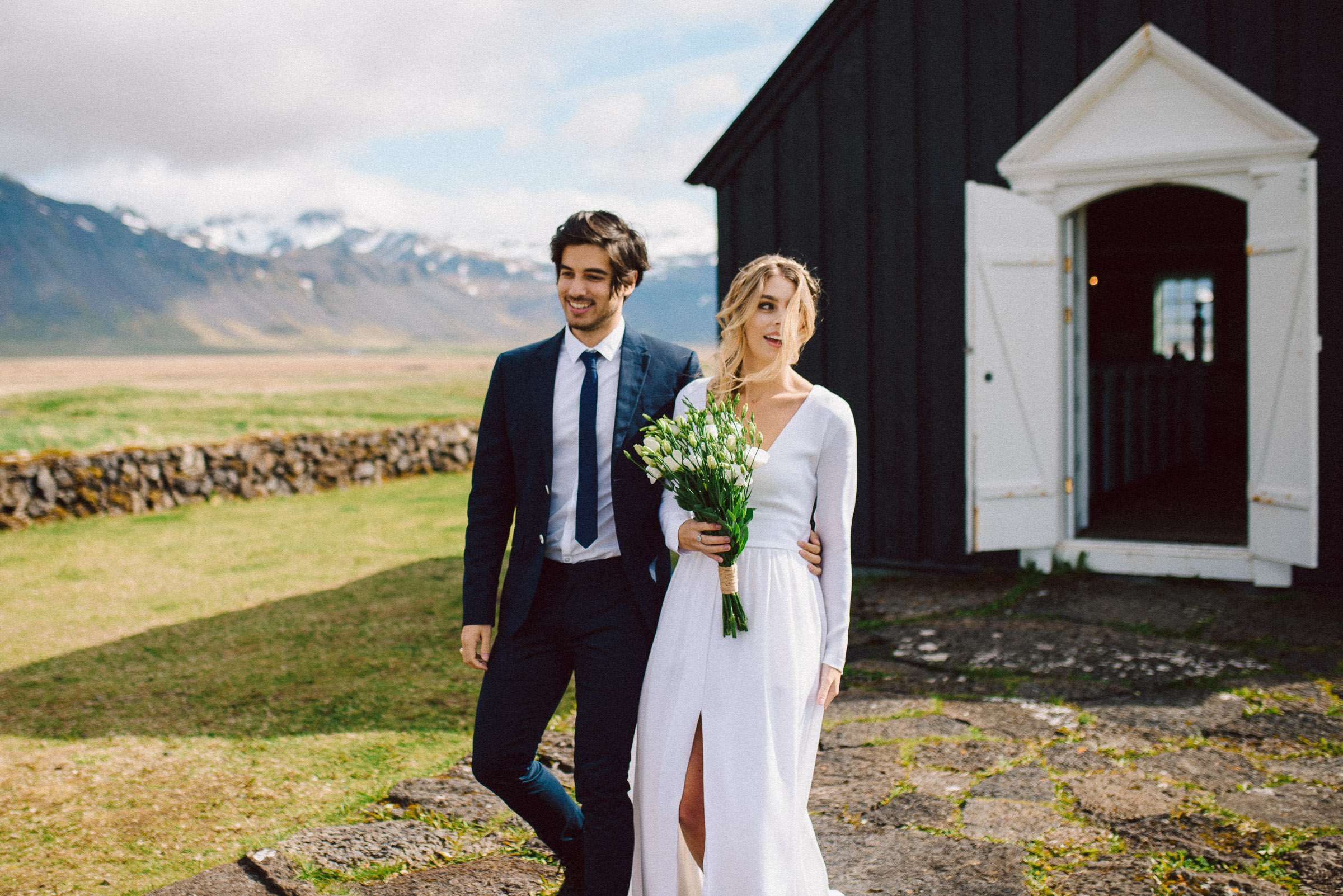 Island-Hochzeit: Brautpaar Arm in Arm vor der Kirche