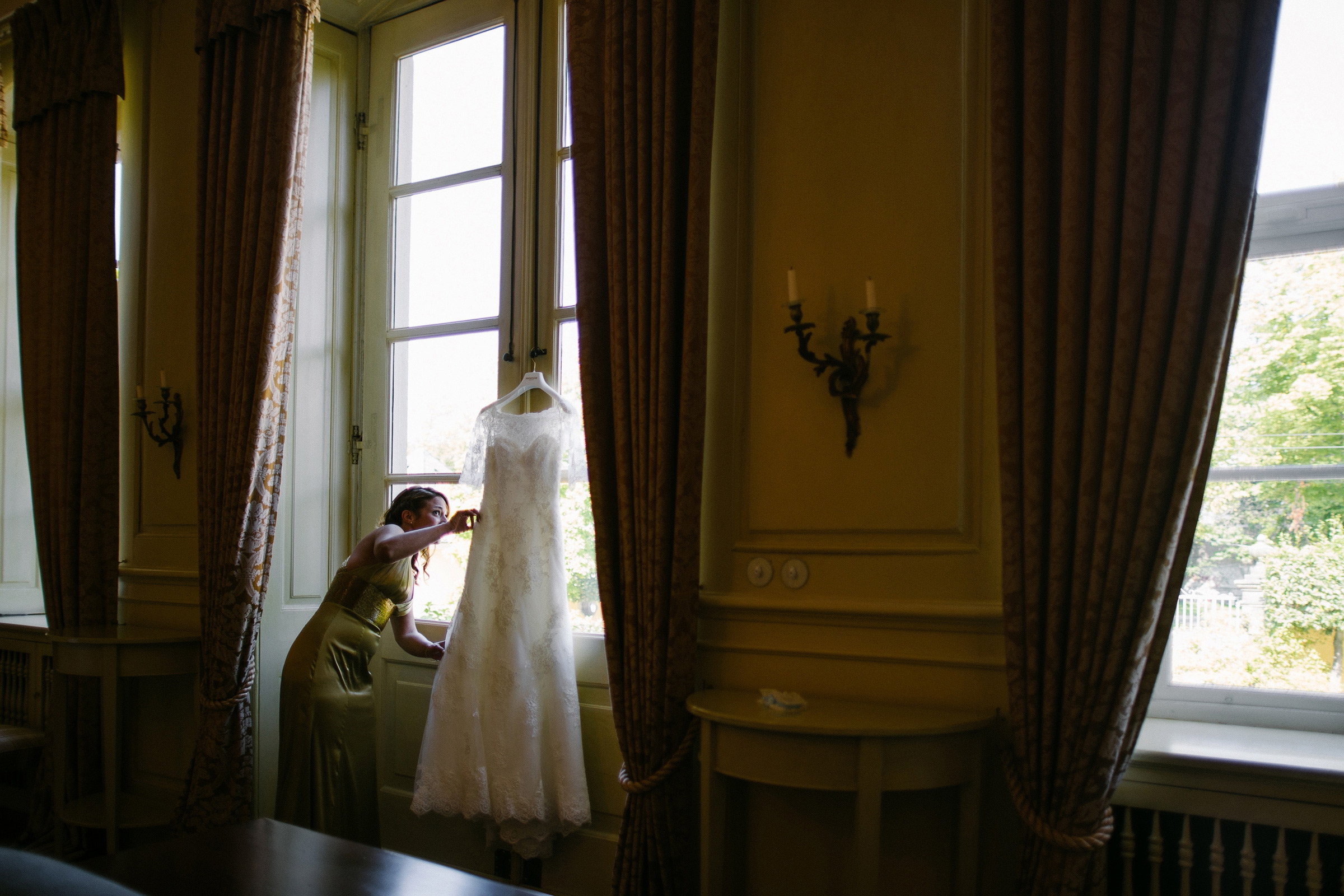 Burghochzeit: Brautkleid hängt am Fenstergriff des Hotelfensters