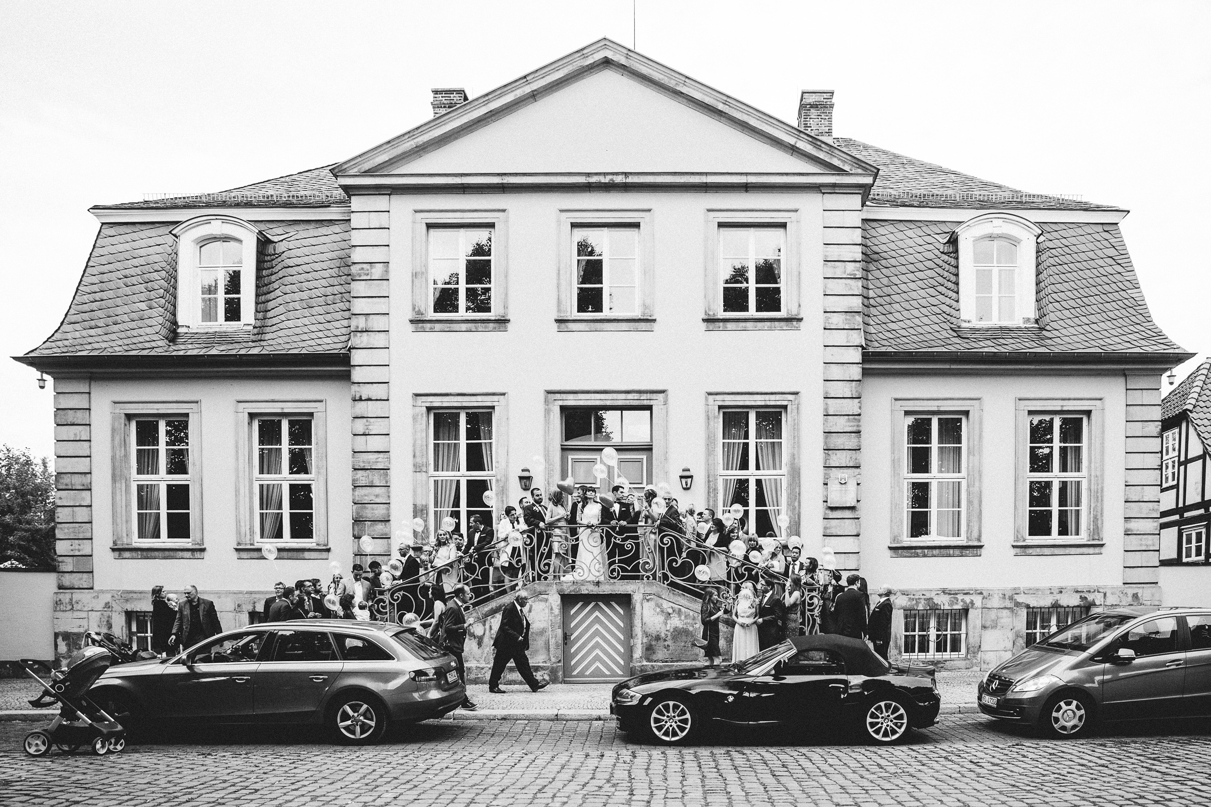 Burghochzeit: Hochzeitsgesellschaft auf der Eingangstreppe des Hotels mit Ballons in der Hand