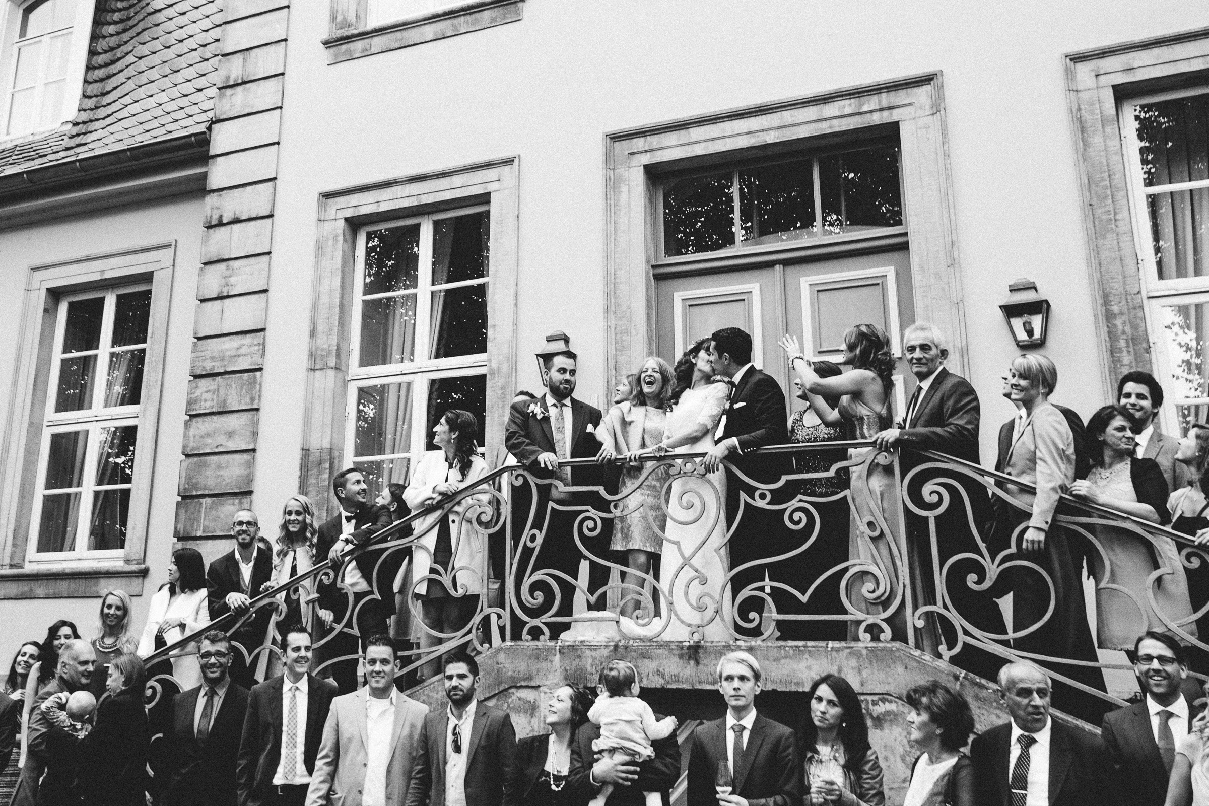 Burghochzeit: Hochzeitsgesellschaft auf der Eingangstreppe und küssendes Brautpaar mittendrin