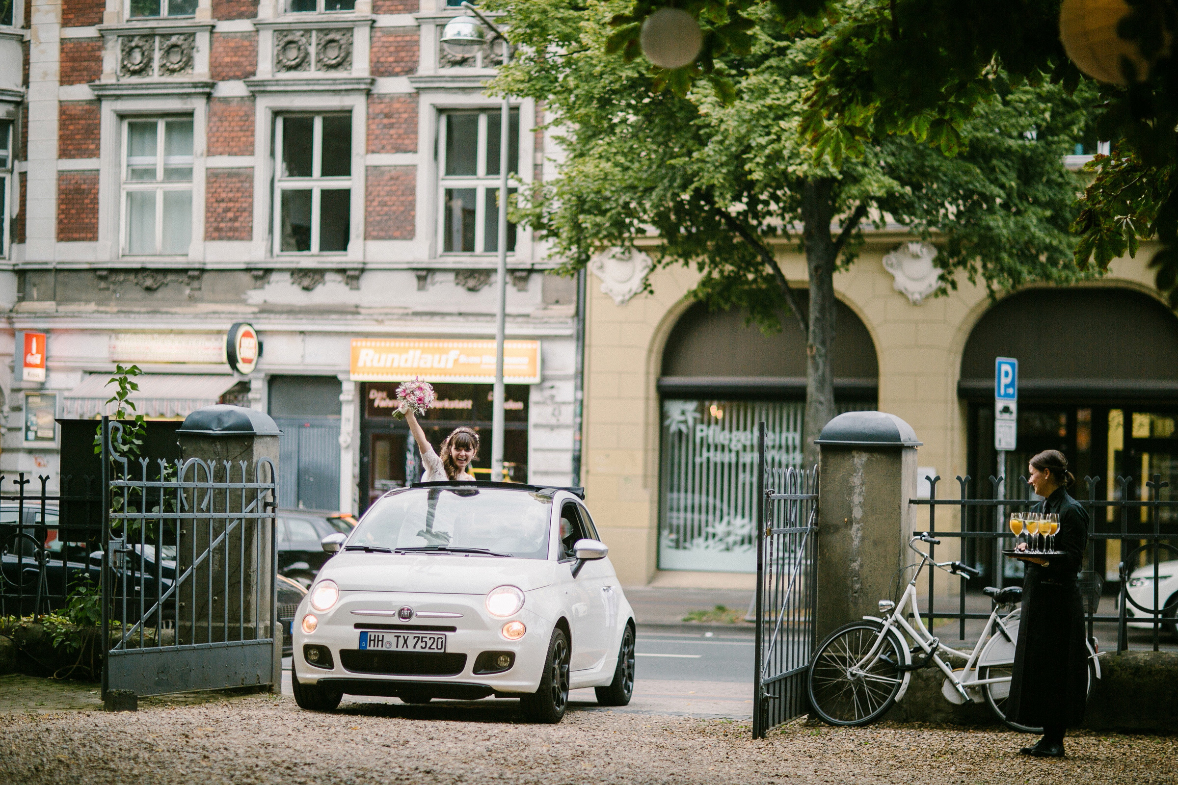 Burghochzeit: Brautauto fährt ein, Braut winkt aus dem offenen Verdeck des Fiat 500