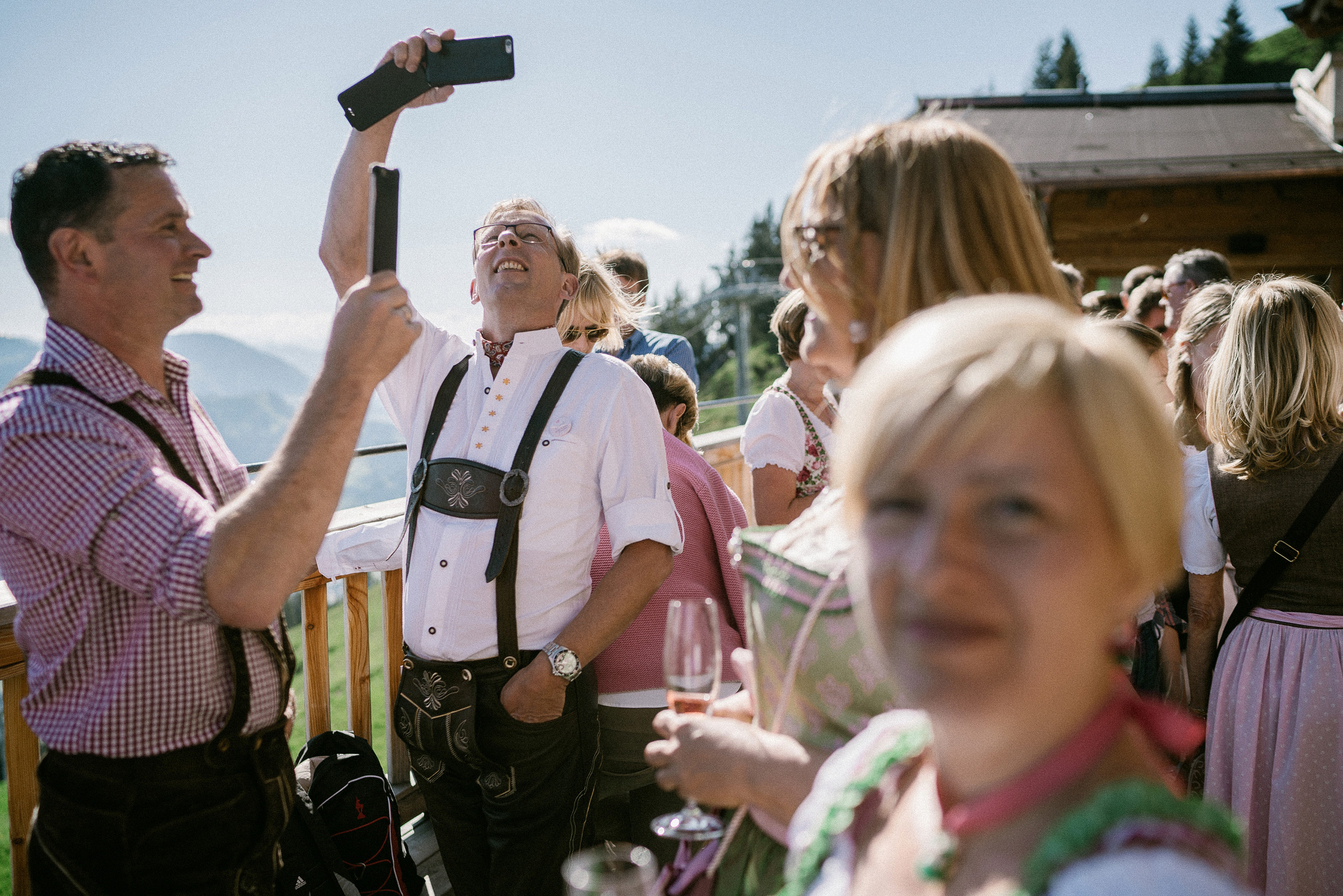 Alpenhochzeit: Hochzeitsgast in Lederhosen fotografiert mit Handy
