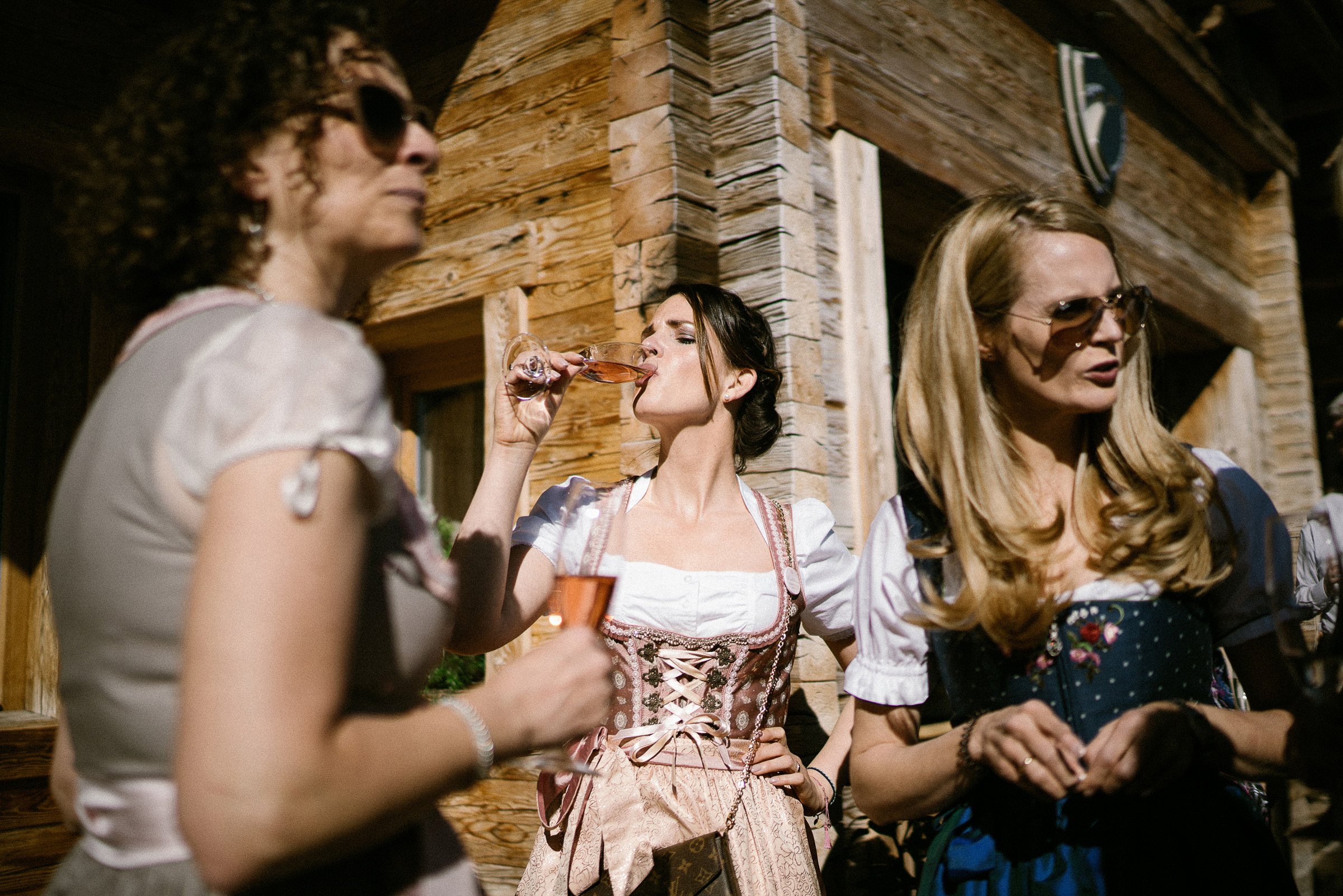 Alpenhochzeit: weiblicher Gast in rosa Dirndl trinkt Sekt