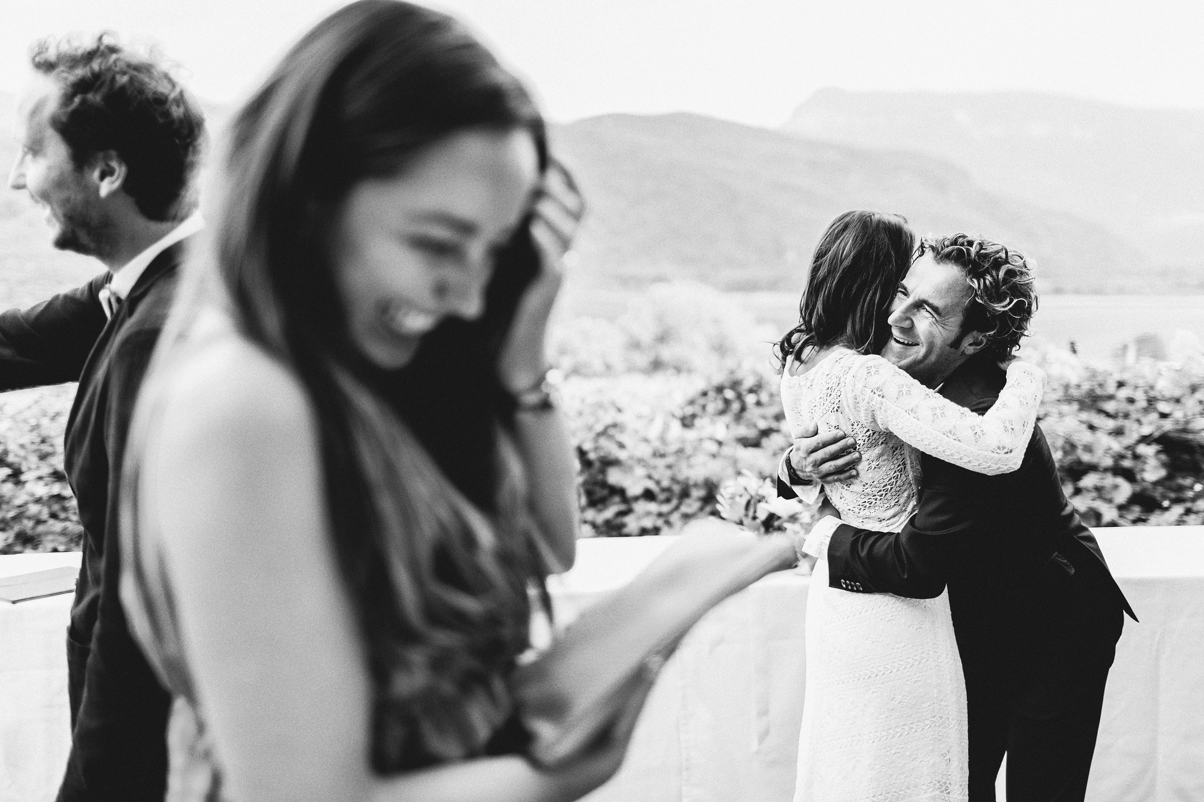 Braut der mediterranen Hochzeit wird umarmt, im Vordergrund lacht eine Frau