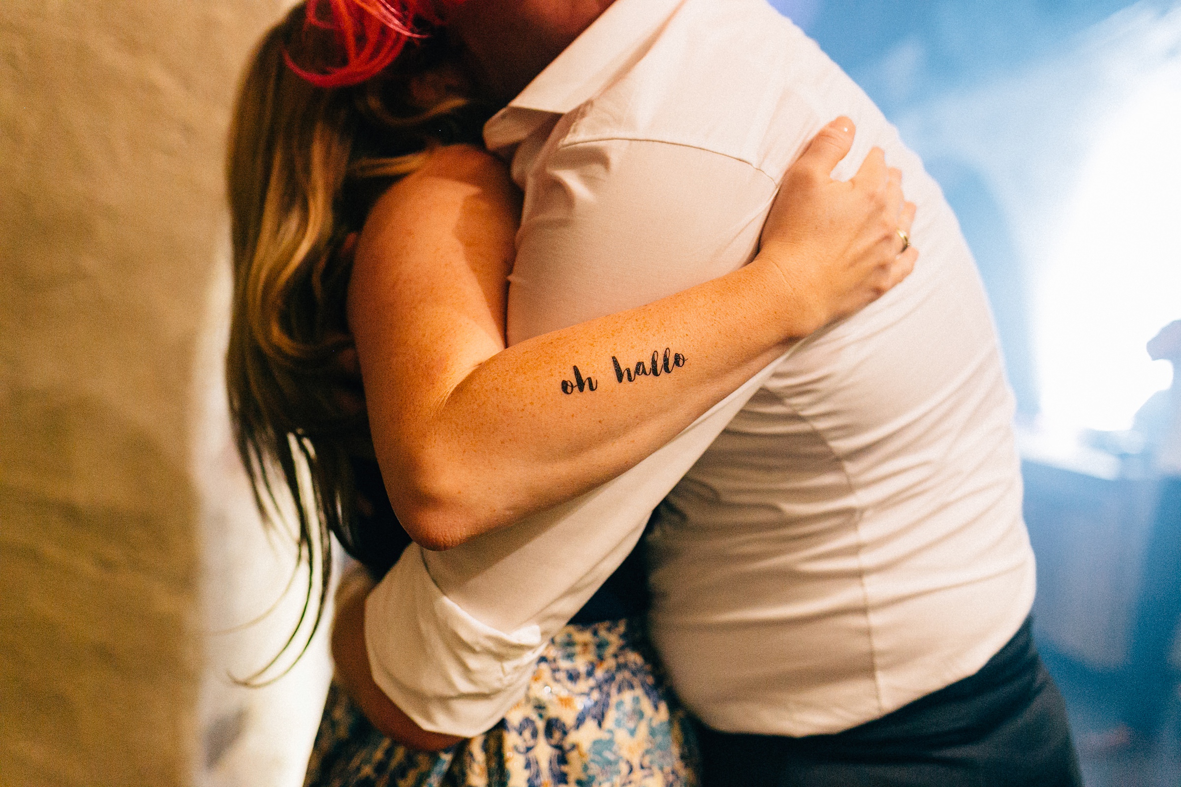 Frau mit "oh hallo" Tattoo umarmt einen Mann
