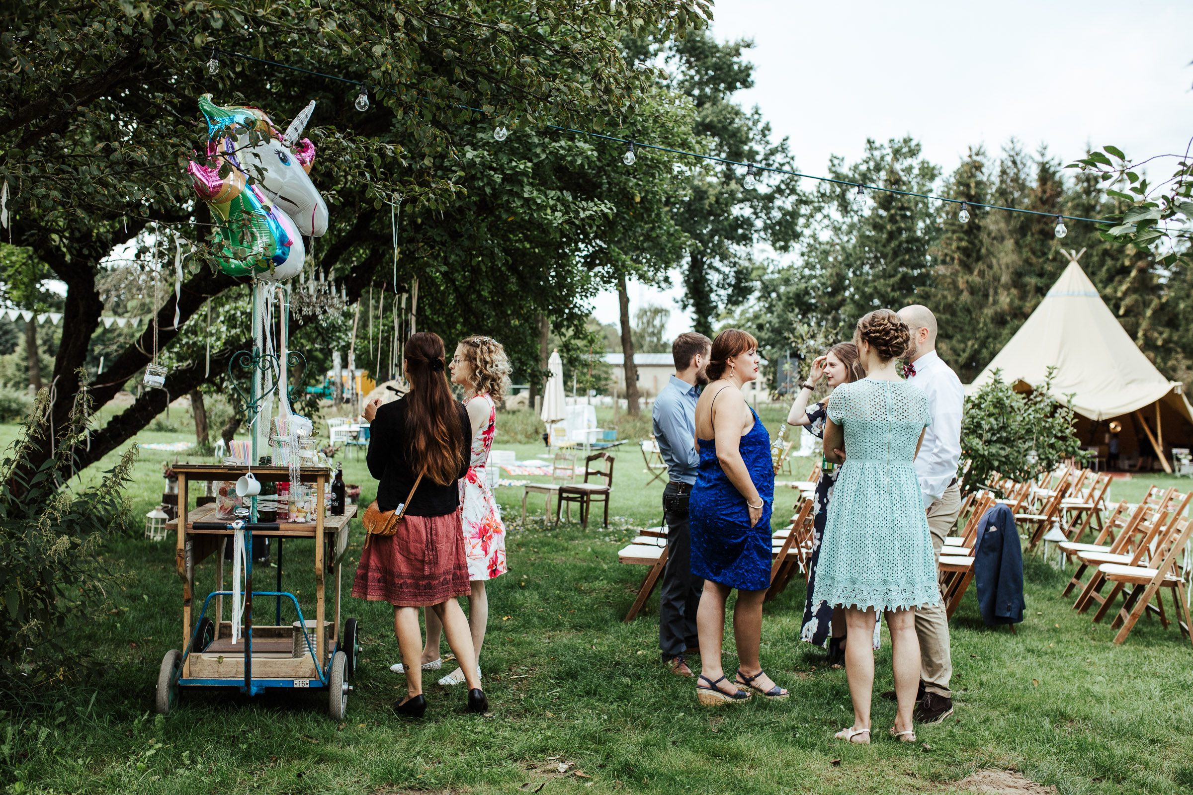 Gäste im Garten der Scheunenhochzeit vor dem Candy-Table