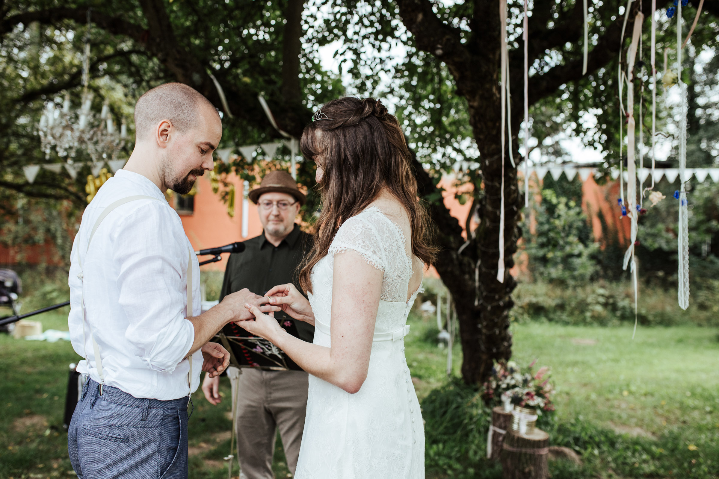 während der Scheunenhochzeit: Braut steckt Bräutigam den Ring an den Finger