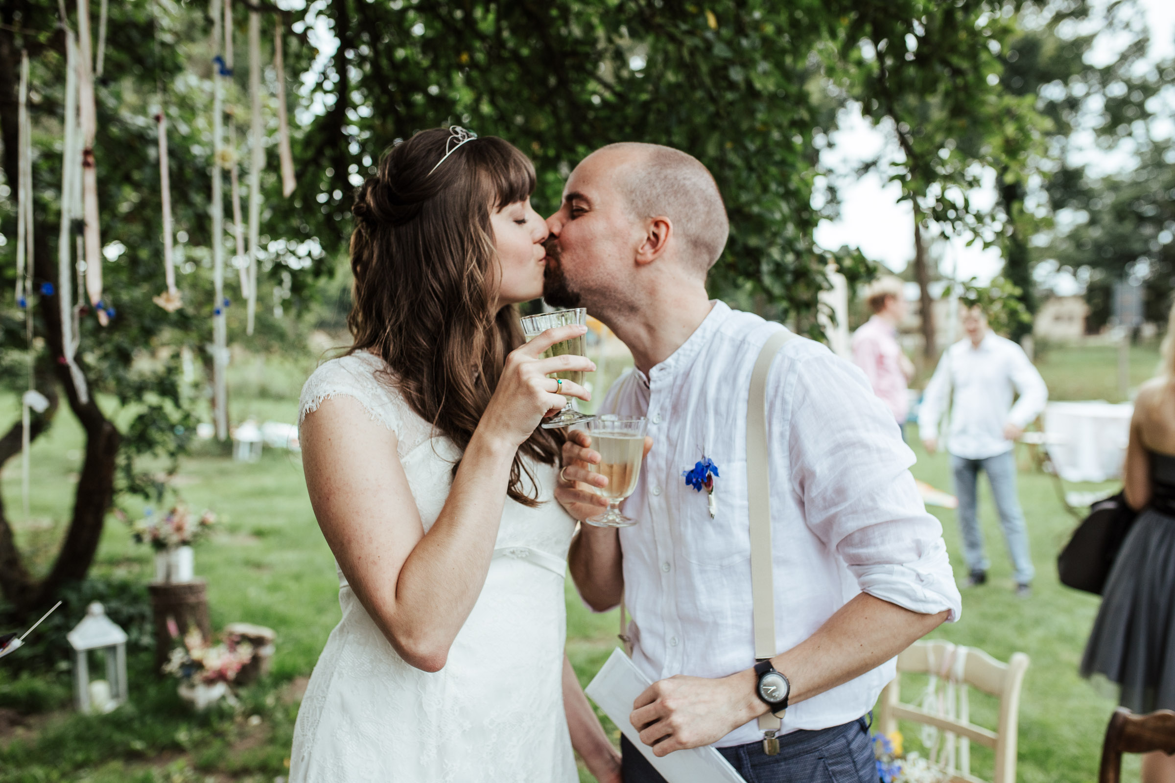 Brautpaar der Scheunenhochzeit küsst sich und hält Sektgläser in der Hand