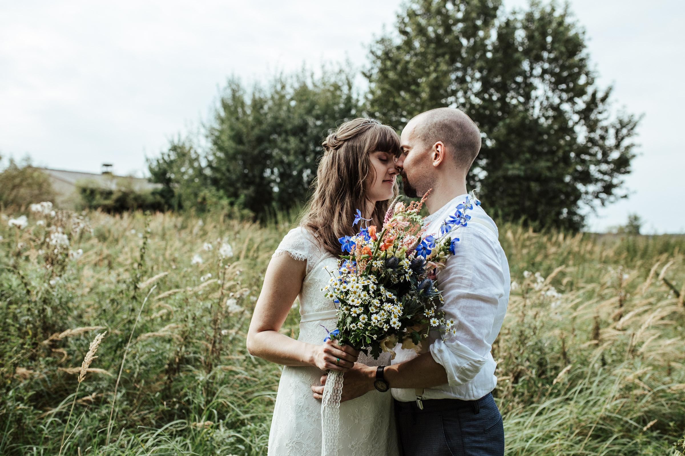 Portrait des Brautpaars, Nase an Nase, im Hintergrund die Scheune der Scheunenhochzeit