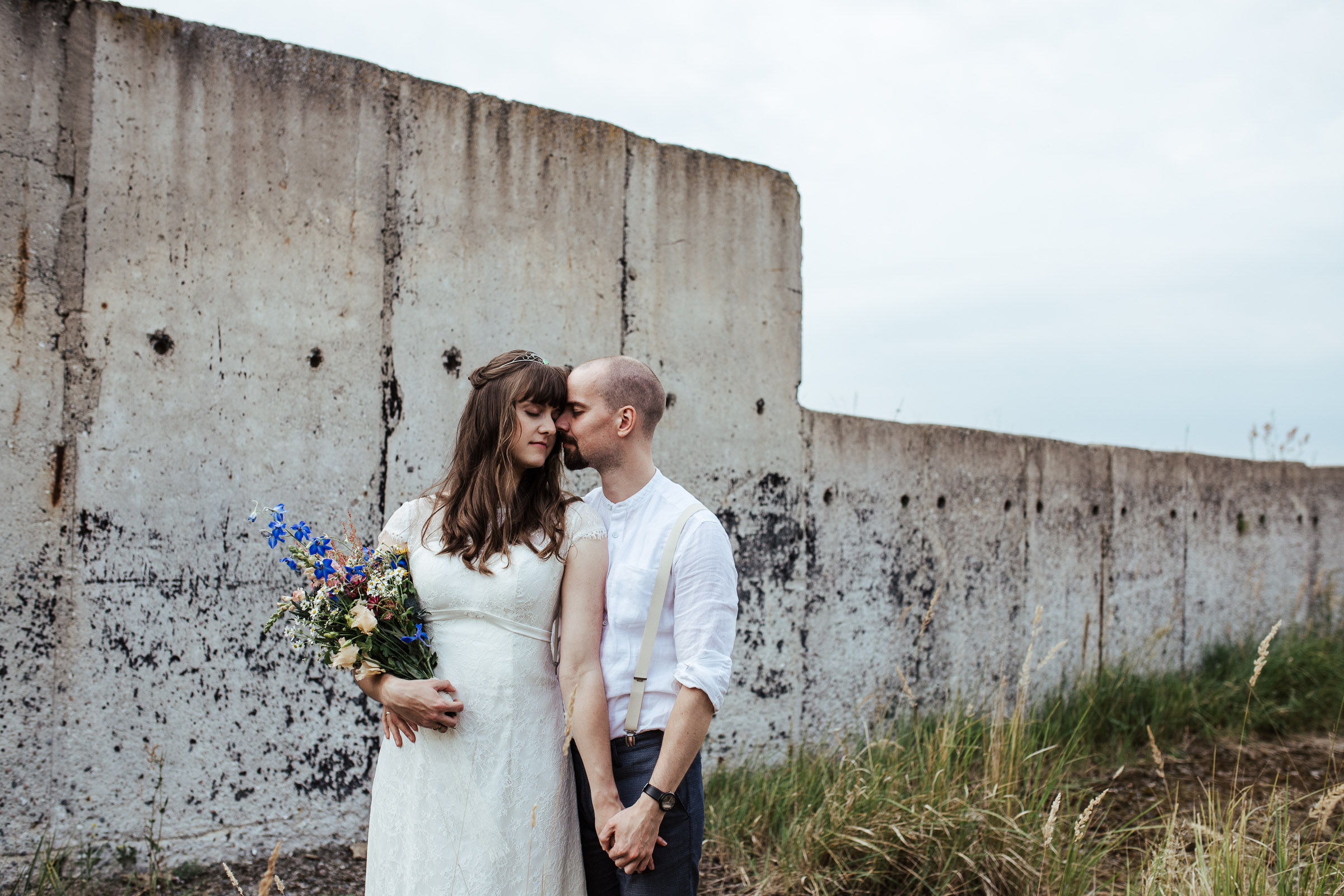 Scheunenhochzeit: inniges Brautpaarportrait vor einer Betonwand