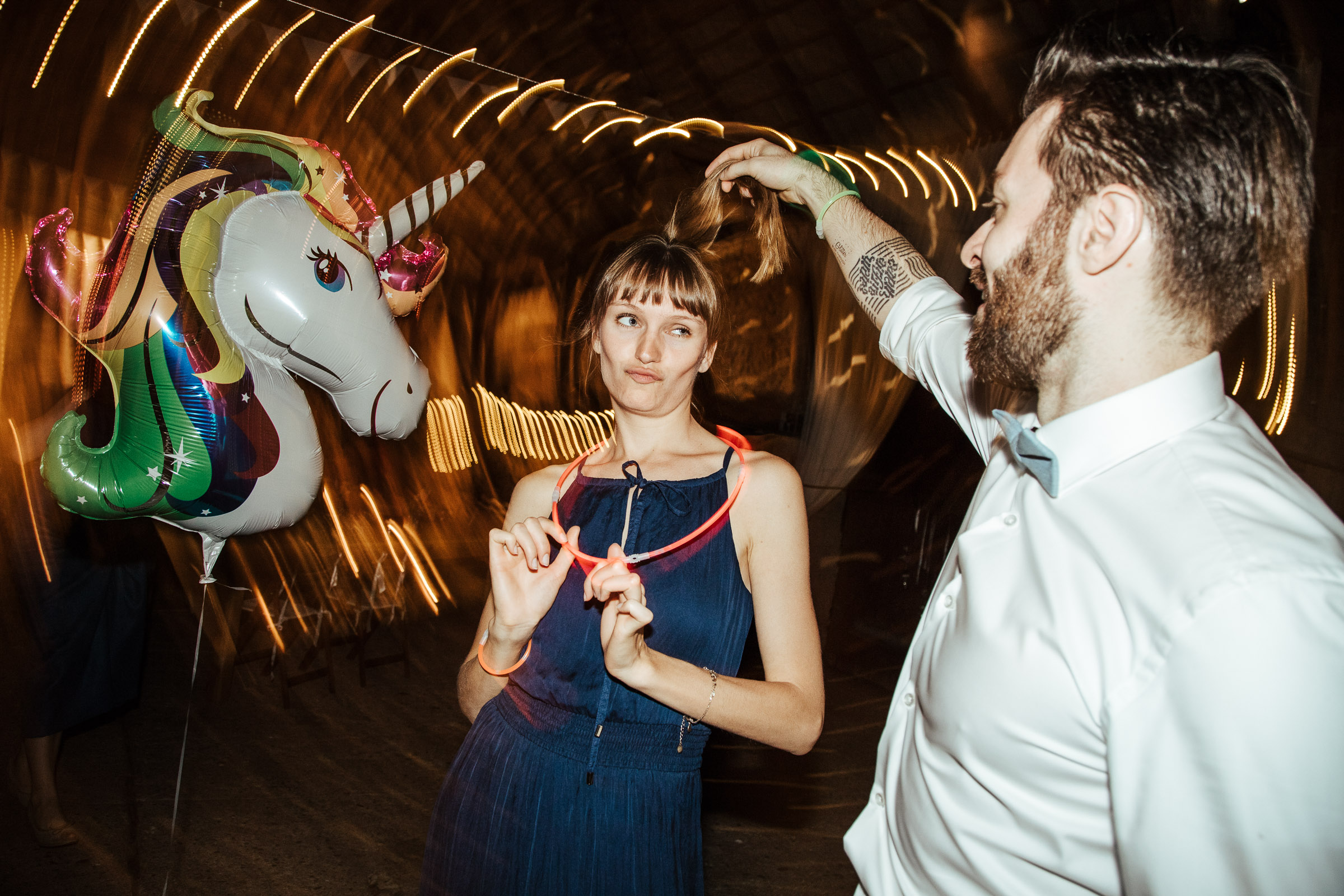 zwei Gäste der Scheunenhochzeit tanzen mit dem Einhorn-Luftballon