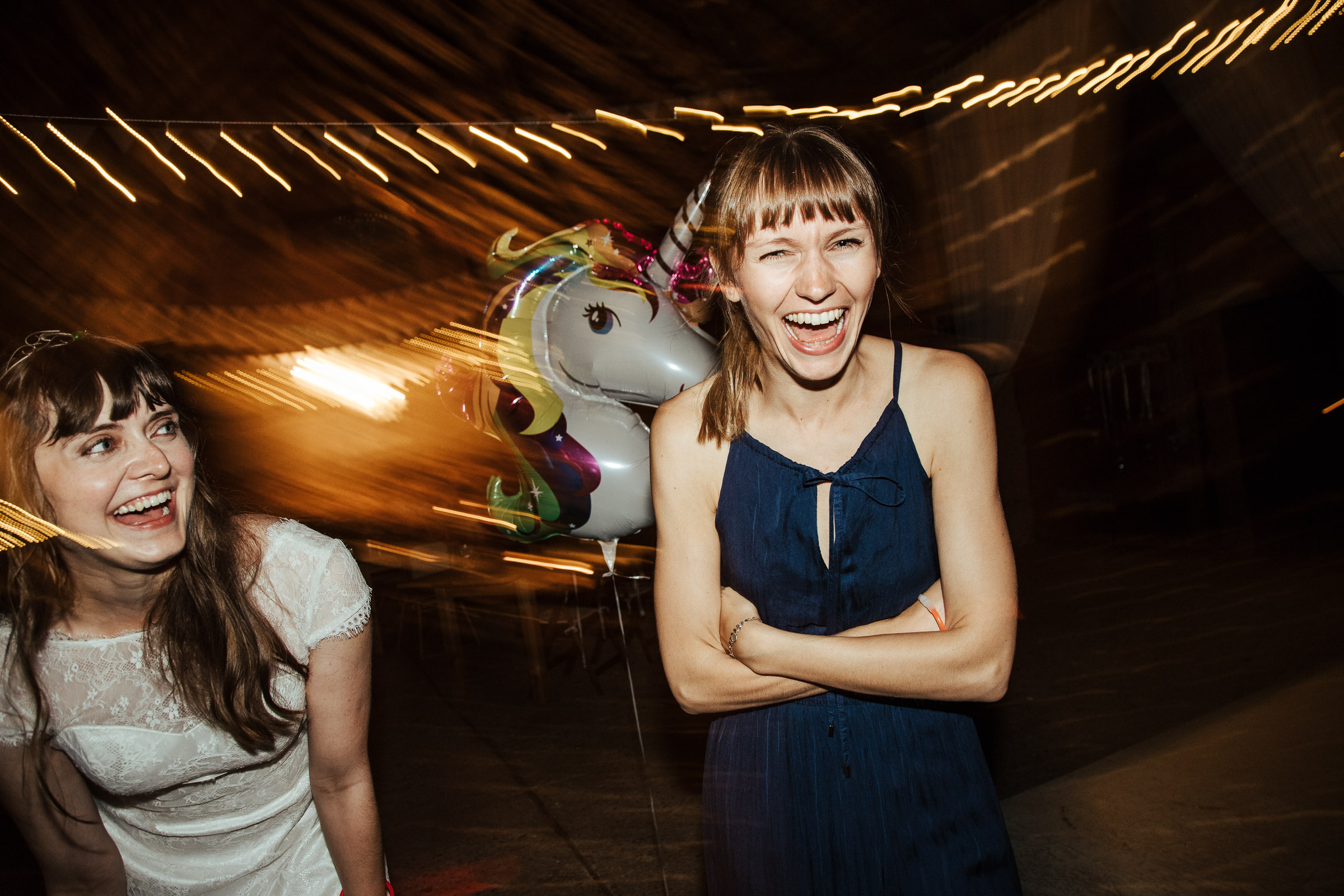 Braut der Scheunenhochzeit tanzt mit Einhorn und einer Freundin