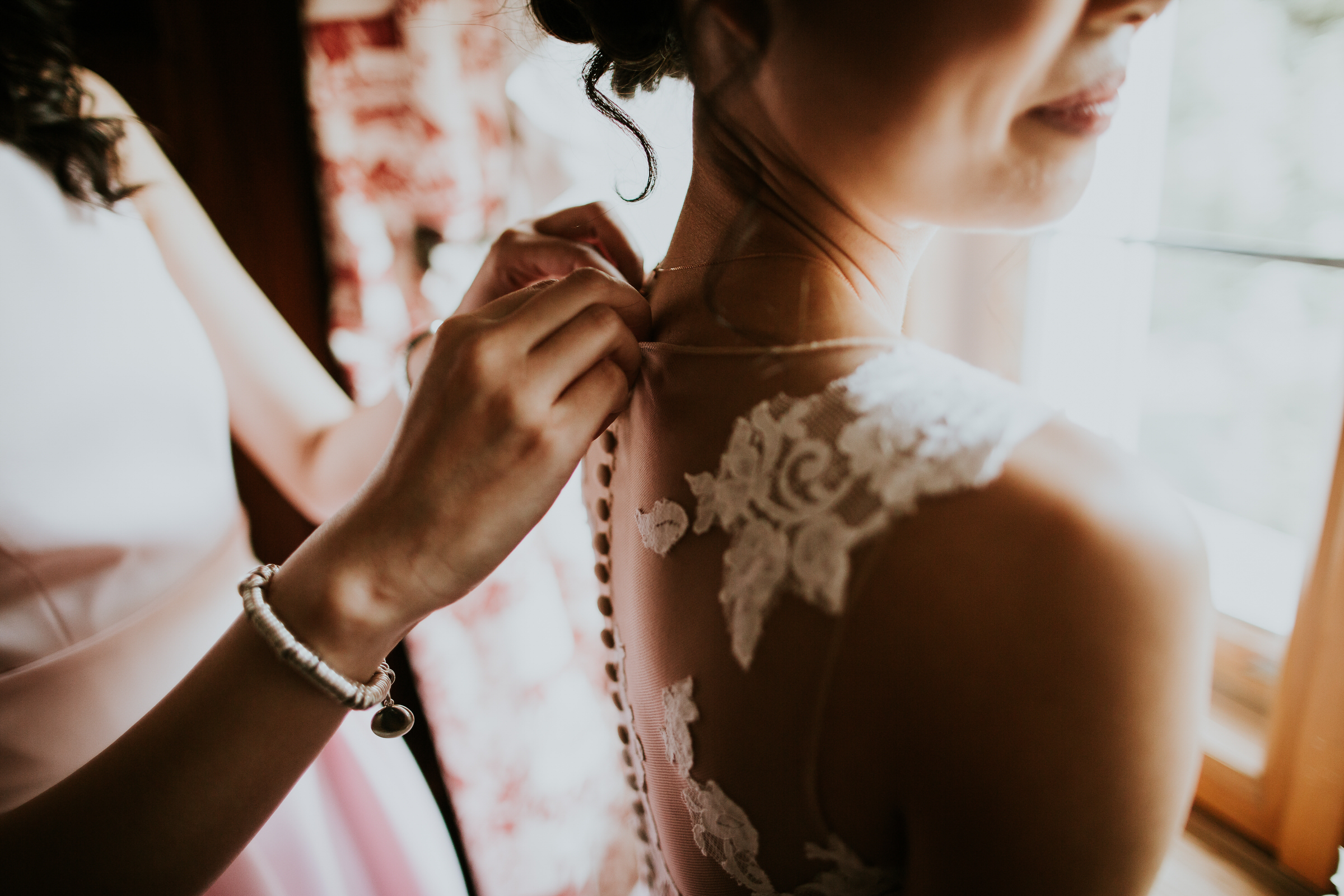 deutsch-chinesische Hochzeit: Brautjungfer knöpft Brautkleid zu