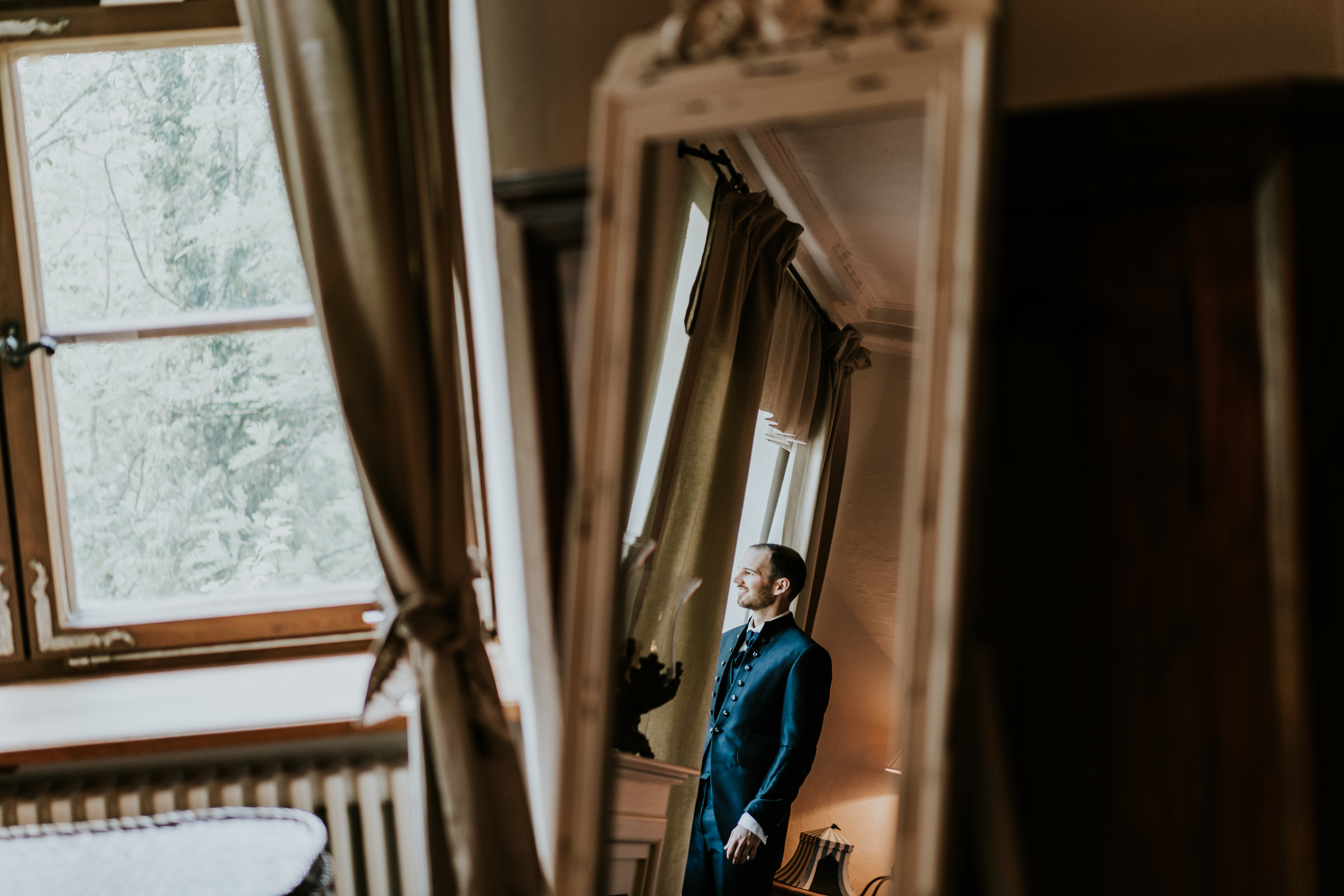 deutsch-chinesische Hochzeit: Bräutigam schaut aus dem Fenster, fotografiert durch einen Spiegel