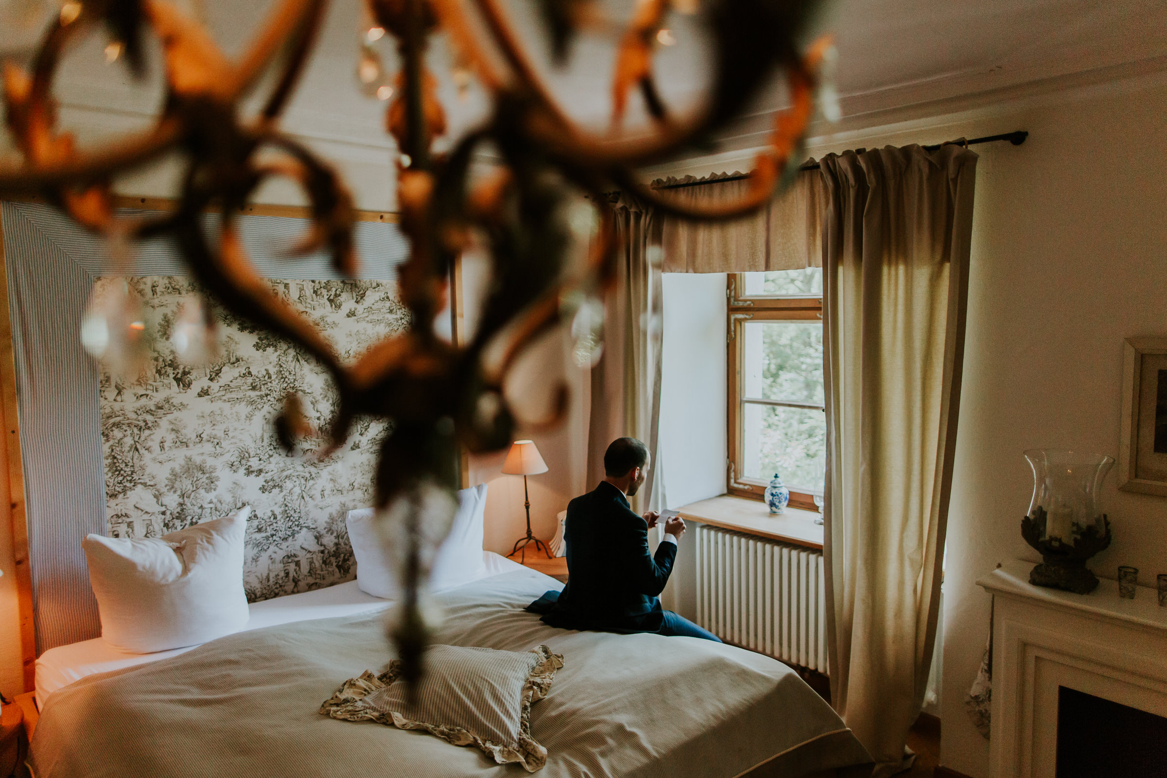 deutsch-chinesische Hochzeit: Bräutigam sitzt auf dem Hotelbett und schaut aus dem Fenster
