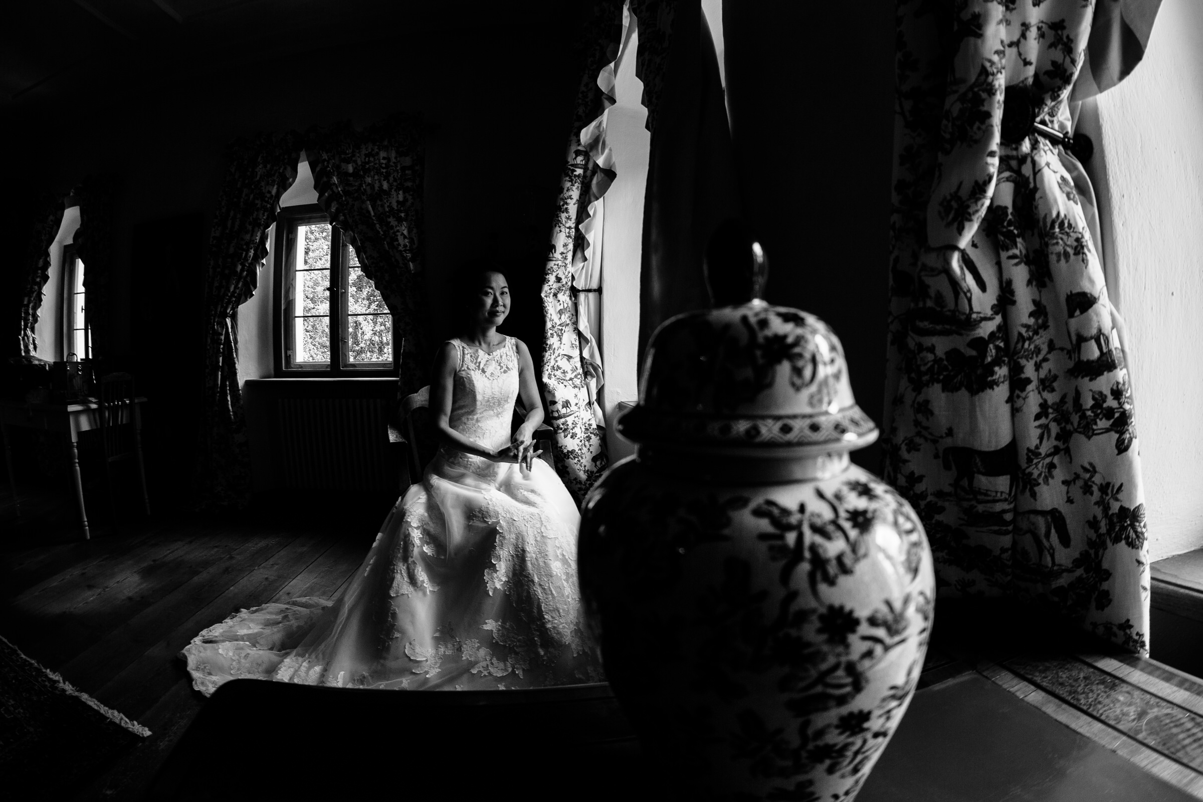 deutsch-chinesische Hochzeit: Braut sitzt vor Fenster im Hotelzimmer 