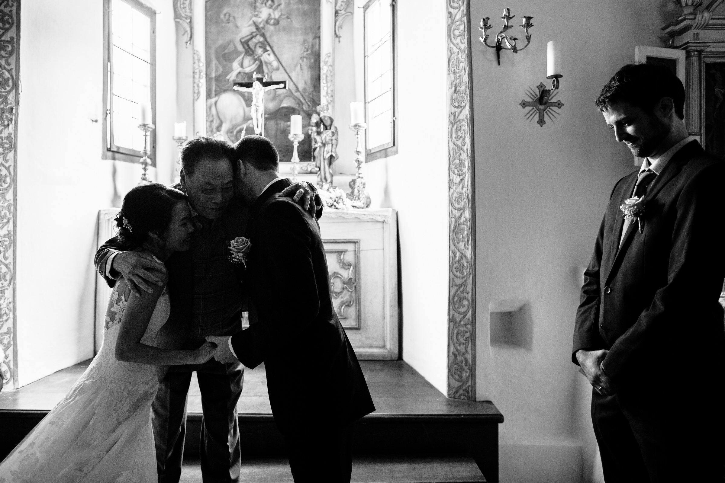 deutsch-chinesische Hochzeit: Brautvater umarmt das Brautpaar am Altar
