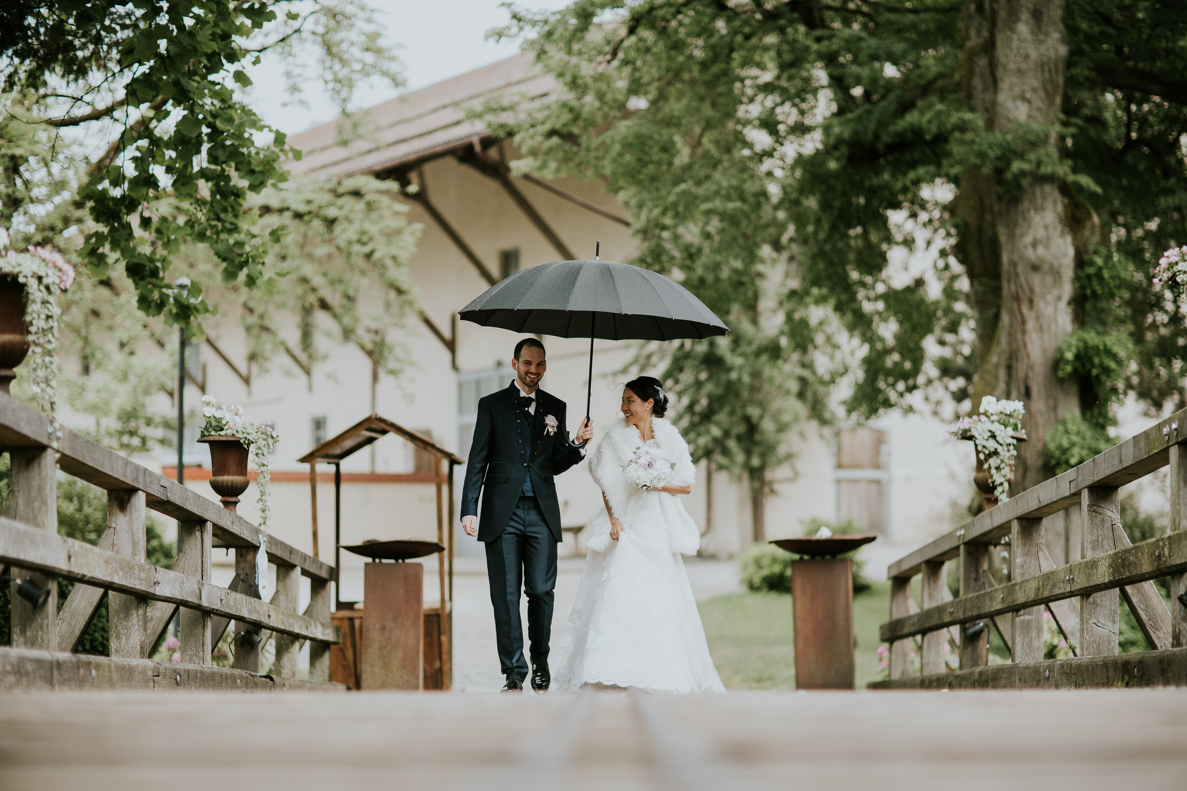 Deutsch-chinesische Hochzeit: Braut und Bräutigam lachend mit Regenschirm