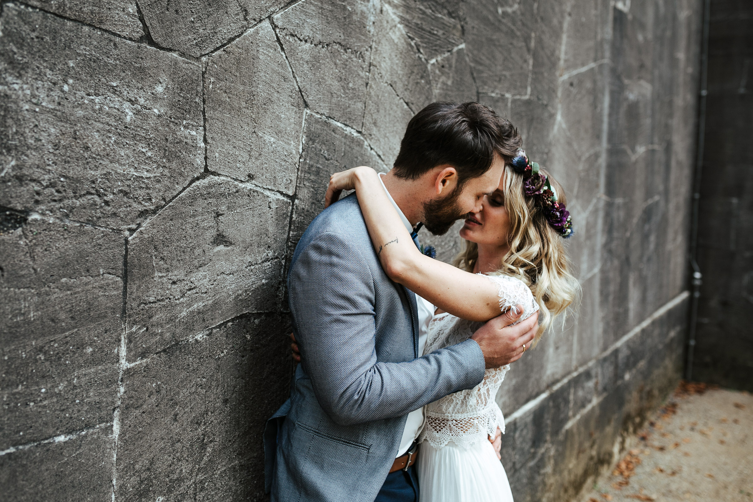 Septemberhochzeit: küssendes Brautpaar vor Steinwand