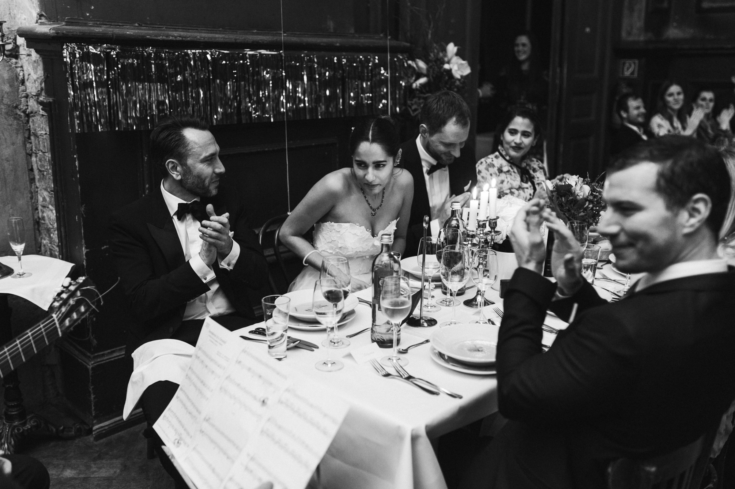 Winterhochzeit: Braut am Tisch mit klatschenden Hochzeitsgästen