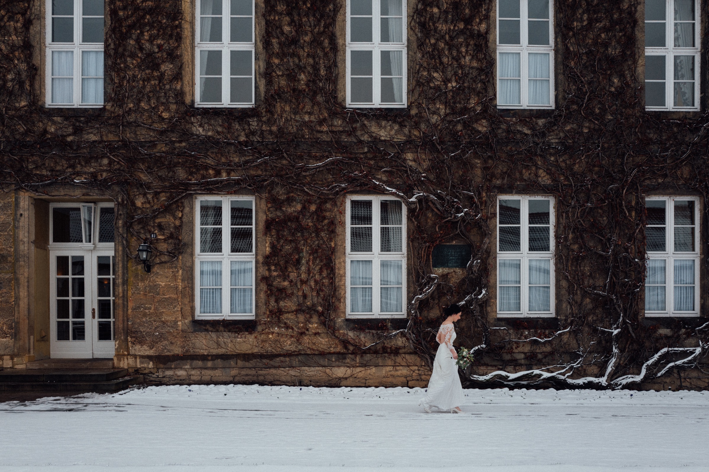 Winterhochzeit: Braut im Schnee vor dem Droste-Haus im Gräflichen Park