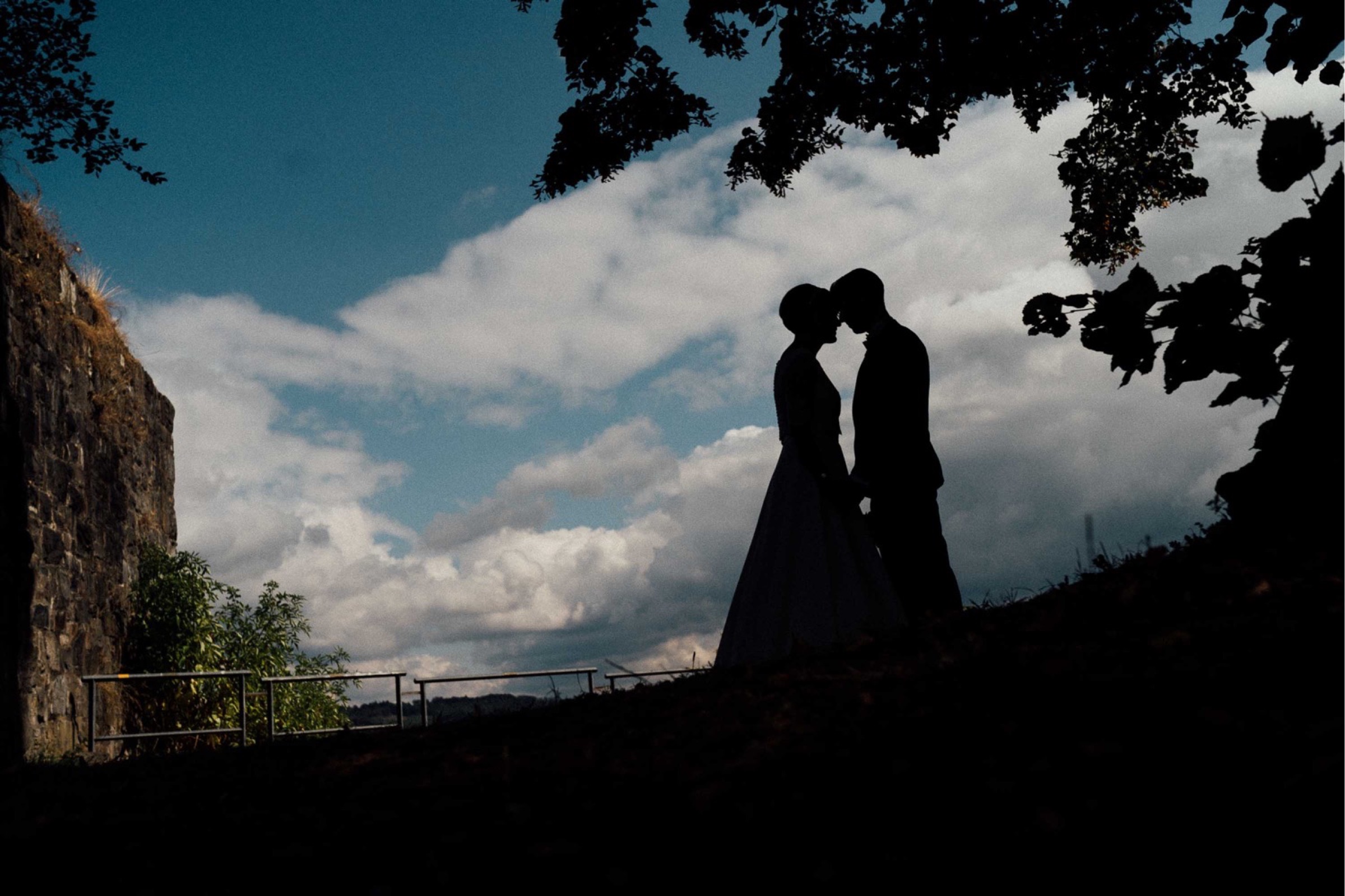 Herbsthochzeit: Silhouette des Brautpaars, vor blauem Himmel mit Wolken